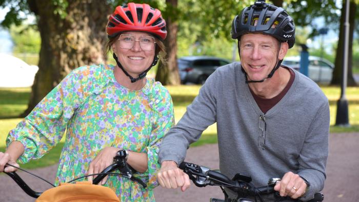 En kvinna och en man står vid varsin cykel med hjälm på huvudet.