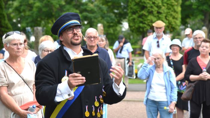 En man läser dikter för en kyrkogårdspublik