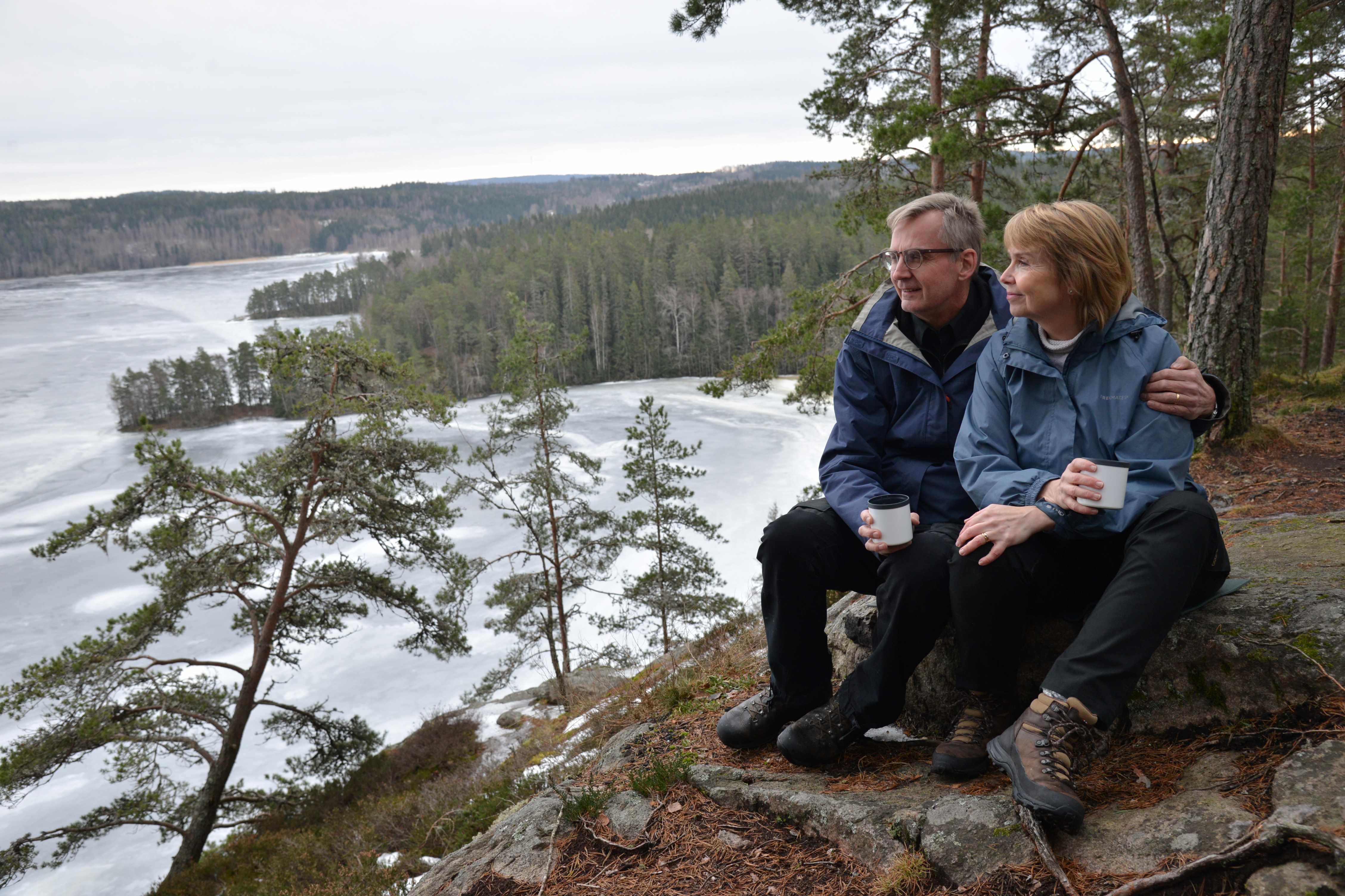 En man och en kvinna sitter på en stenhäll och fikar