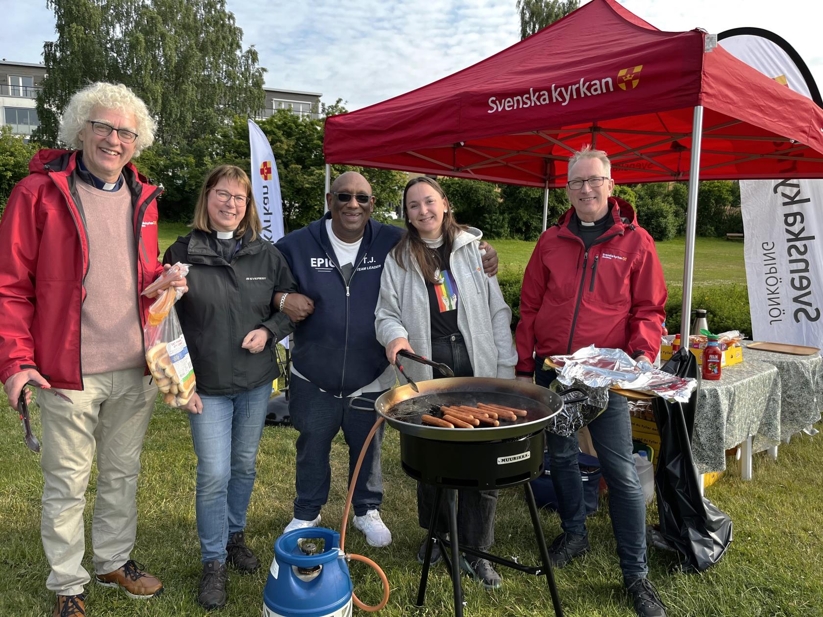 Fem personer står runt en grill