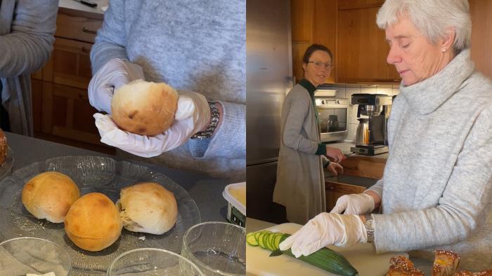 En person brer smörgåsar, en kvinna skär gurka. 