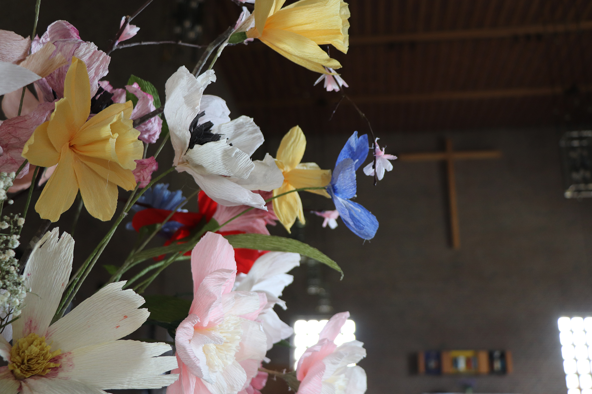 Sommarblommori papper, ett kors på vägen syns i bakgrunden.