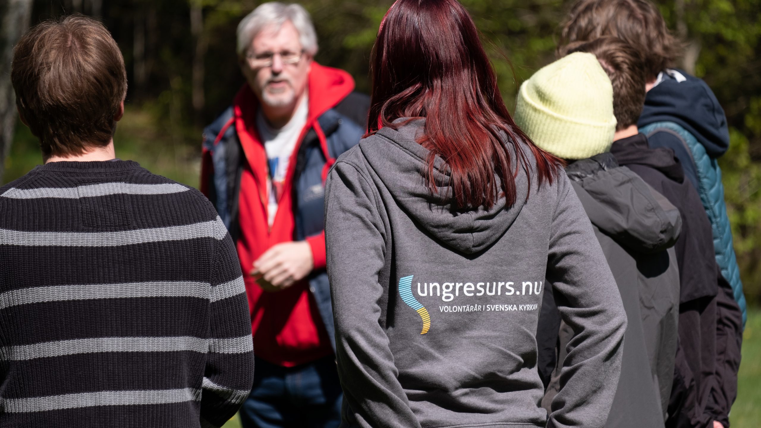 Några personer står och pratar, en person har en tröja med texten "Ung resurs" på ryggen. 