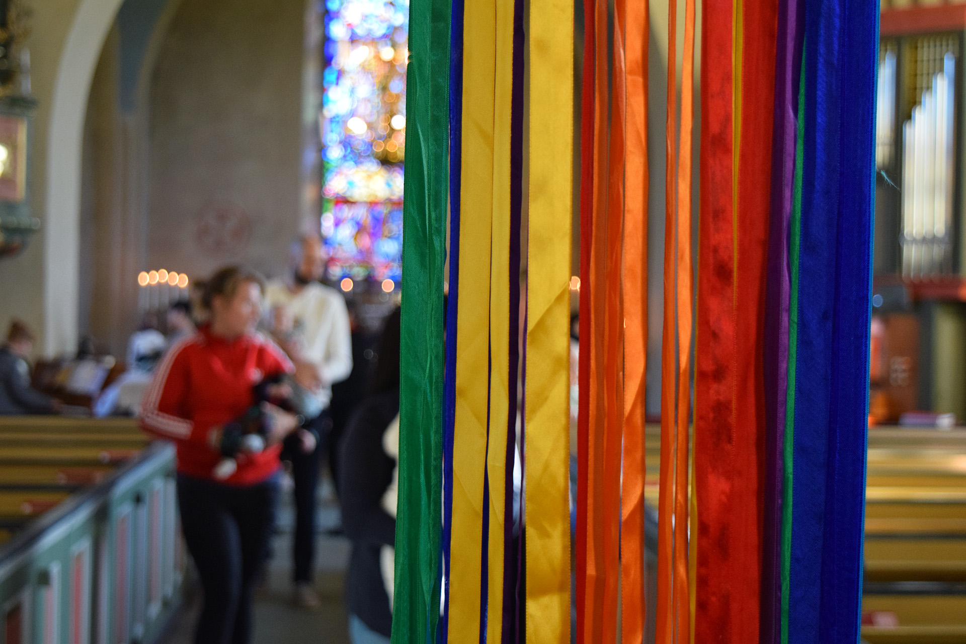 I förgrunden syns en mobil färgglada sidenband, upphängd  under en upplevelsevandring i Valbo kyrka.