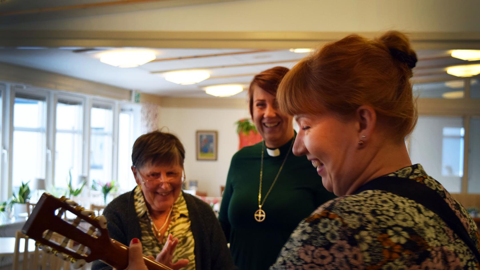 Person från kyrkan sjunger och spelar tillsammans med boende på serviceboende.