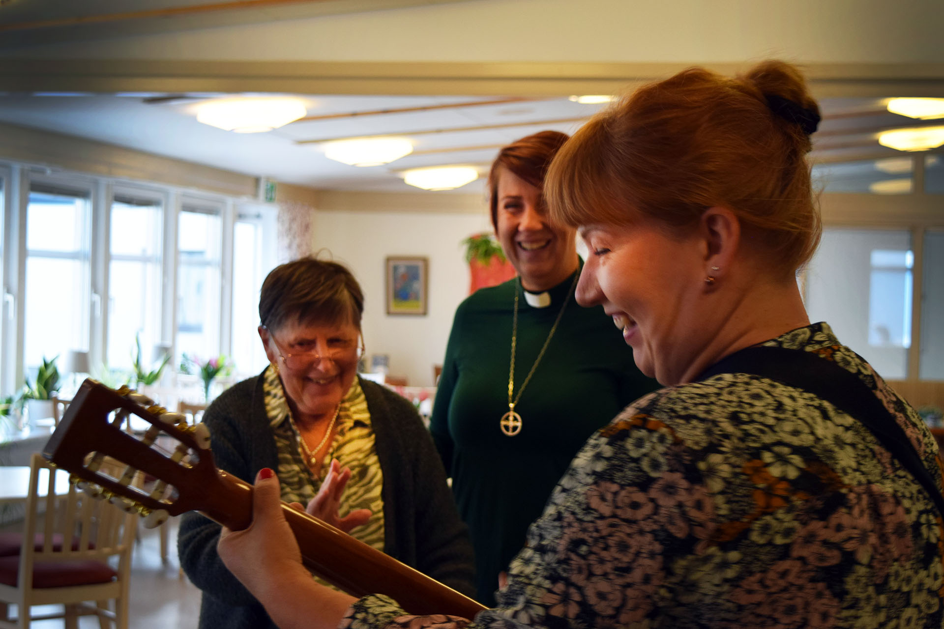 Person från kyrkan sjunger och spelar tillsammans med boende på serviceboende.