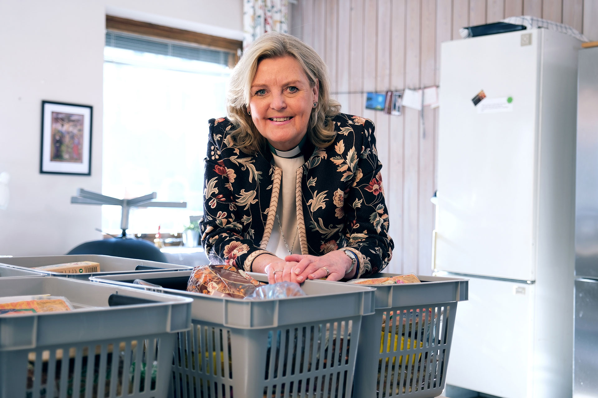 Catarina Granath, diakon, står vid grå matkorg av plast. 