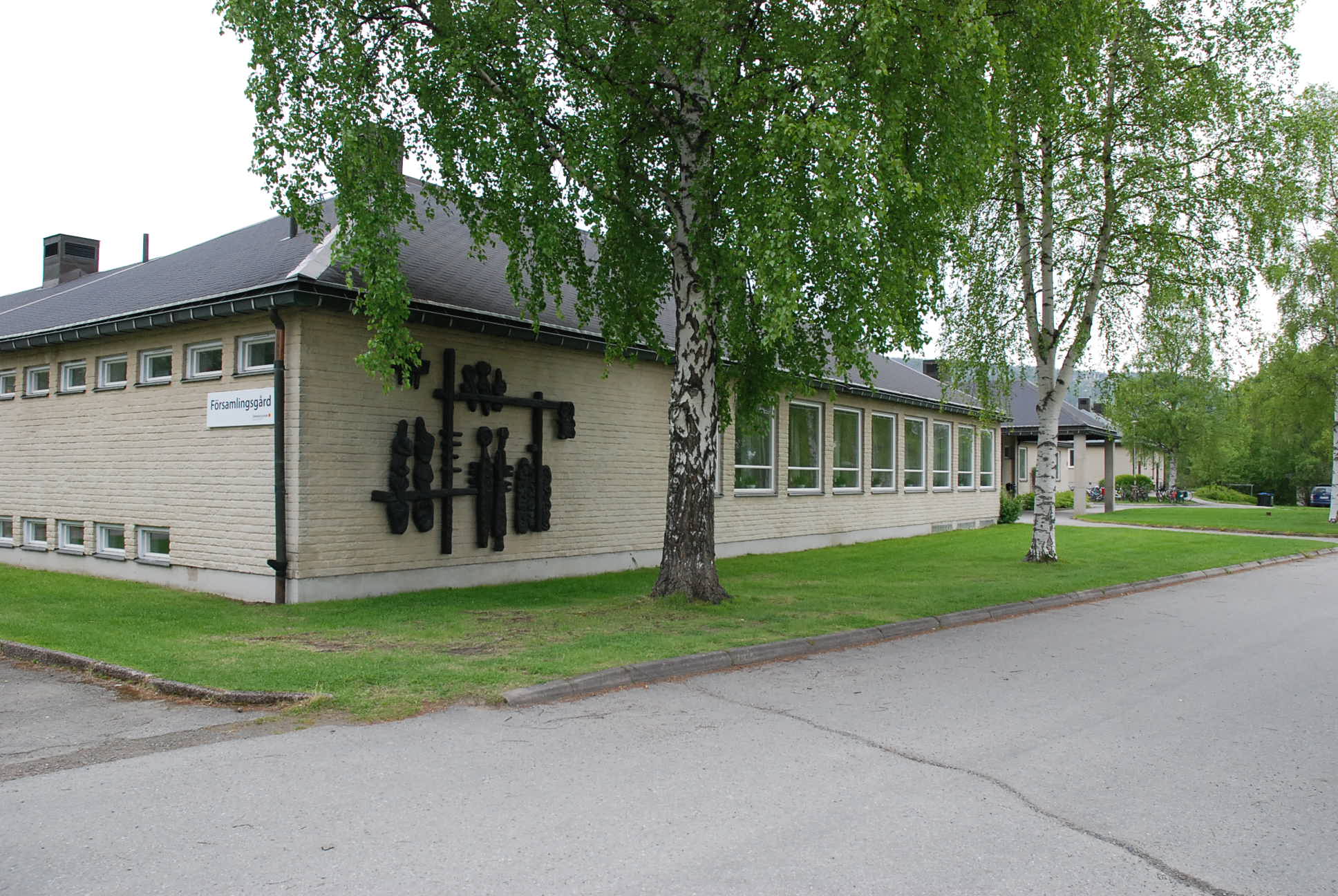 Framsidan av Sollefteå församlingsgård. Byggnaden omgiven av försommargröna björkar.