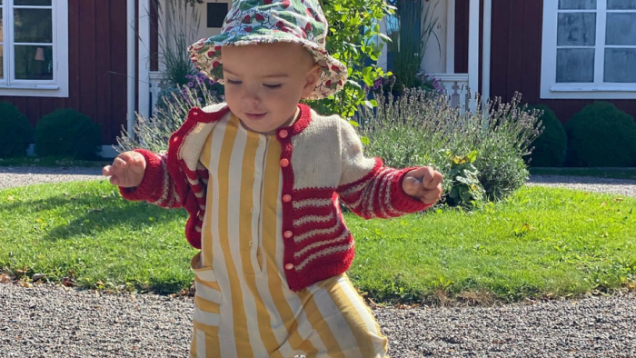 Ett litet barn går omkring framför Klockarbacken en fin sommardag