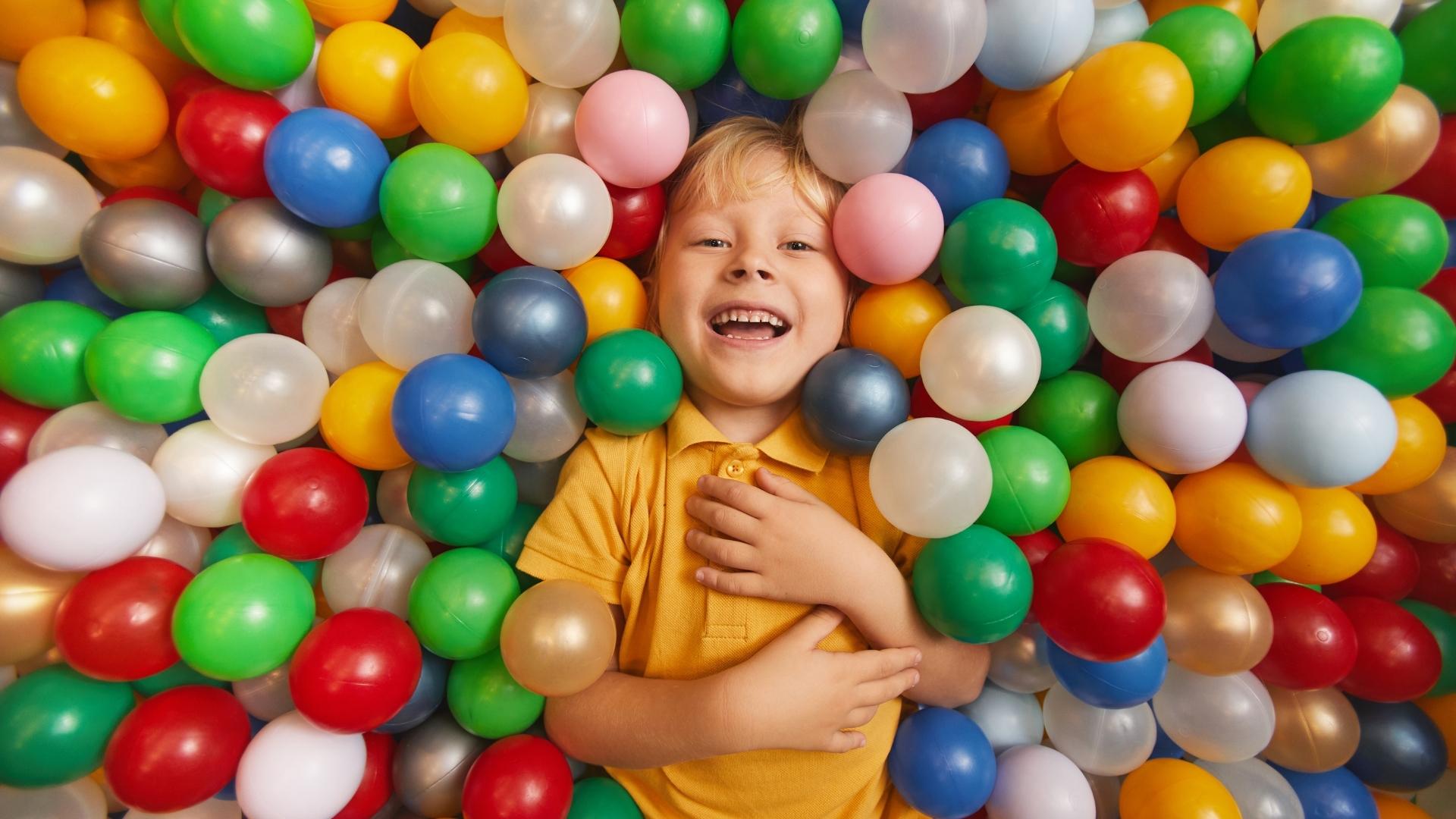En pojke som ligger i en stor hög med småbollar