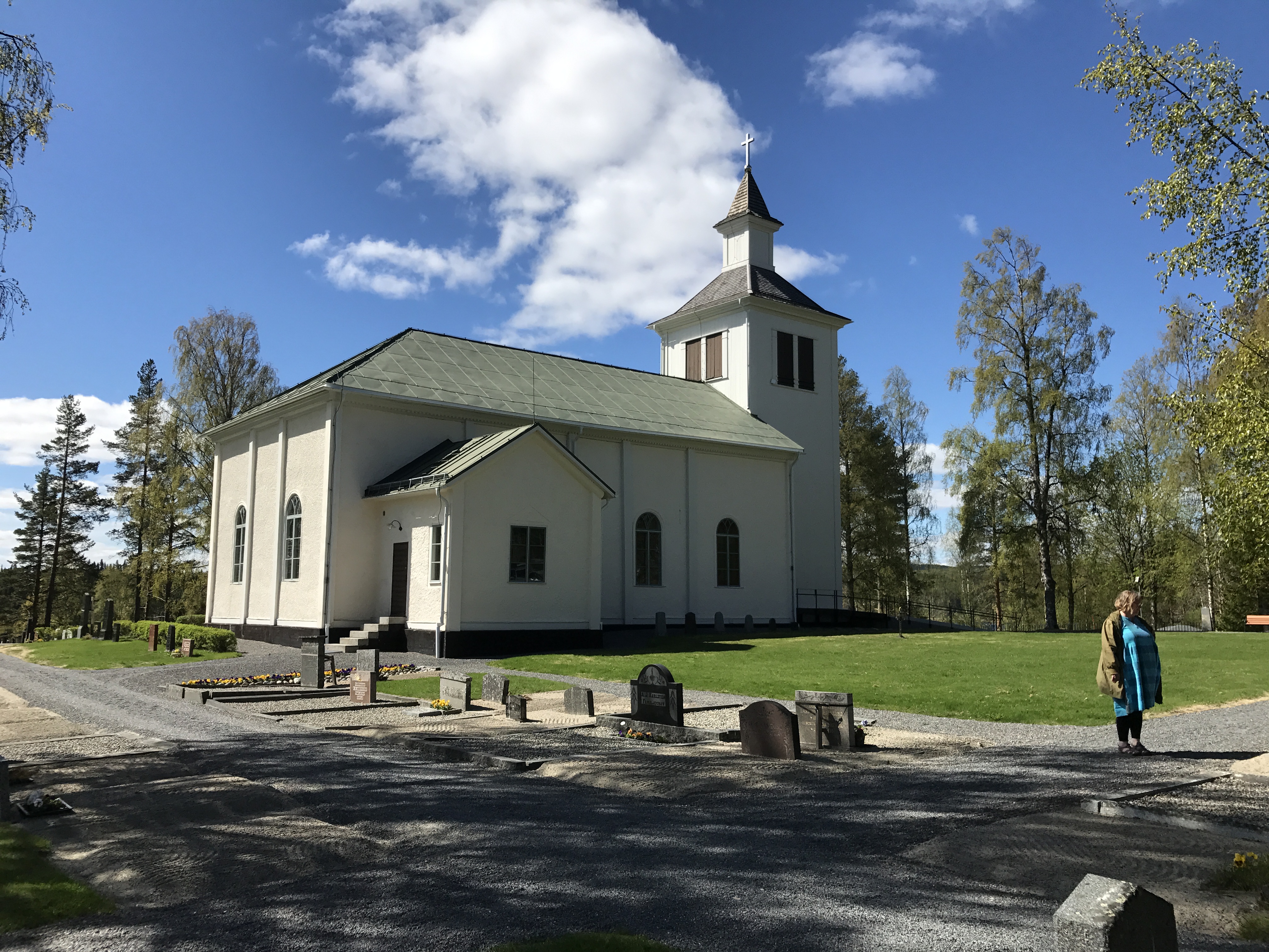Exteriörbild av Trehörningsjö kyrka med grönskande bakgrund.