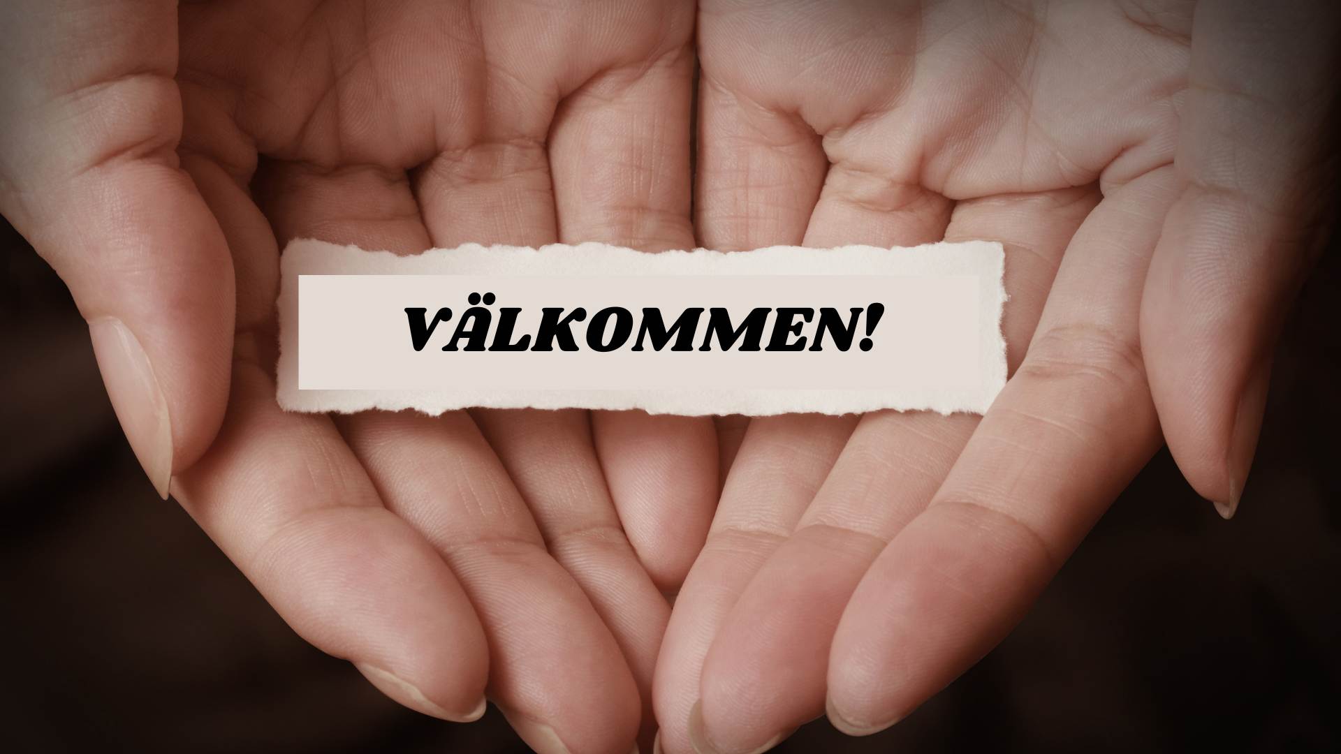 Två öppna händer som har en lapp där det står "Välkommen".