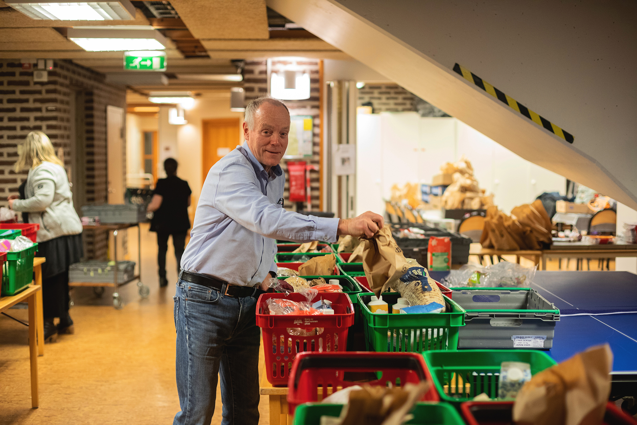 En man som står och packar livsmedel i matvarukorgar