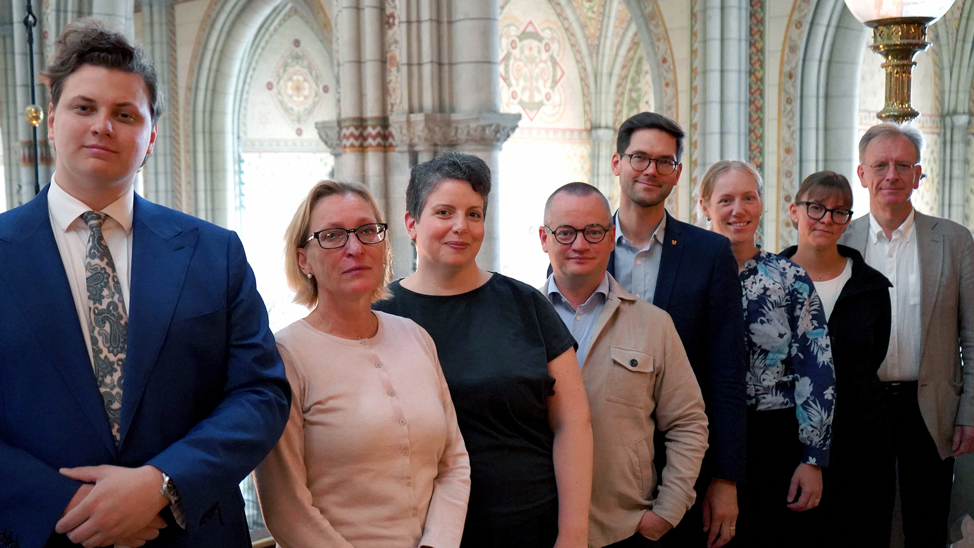 Uppsala domkyrkas åtta medarbetare i musikarbetslaget står på västra läktaren och blickar in i kameran.