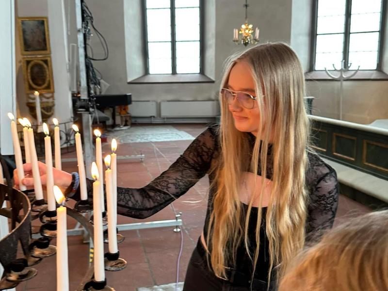 En ung tjej tänder ljus i eb ljusbärare i en kyrka