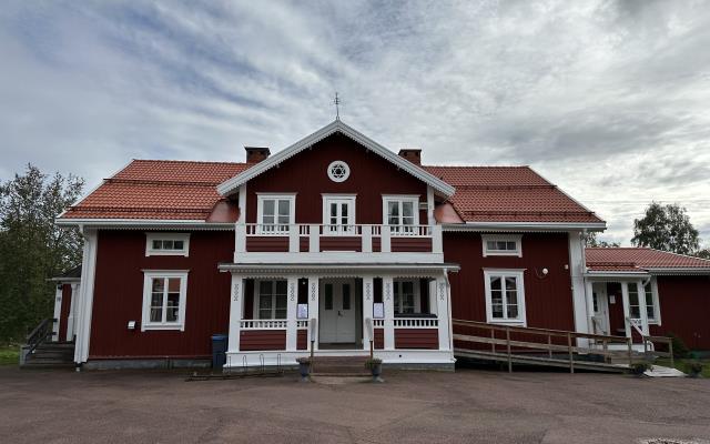 Rött tvåvåningshus med vit balkong, ramp upp till veranda