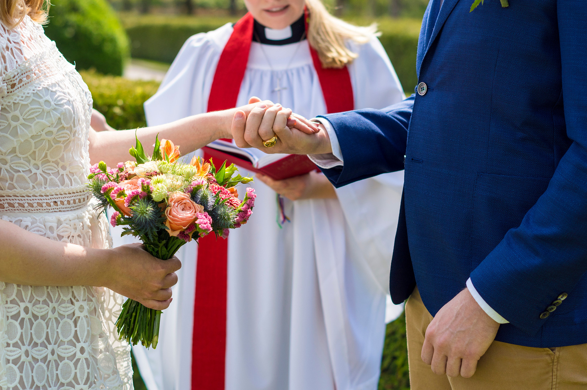 En präst i Svenska kyrkan viger ett brudpar som håller varandra i händerna. 