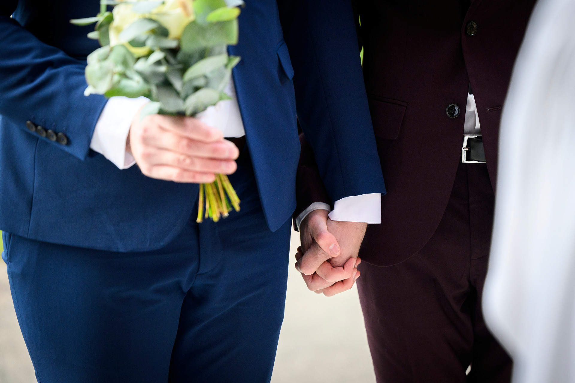 Två män håller varandra i händerna innan de går in i Svenska kyrkan för att gifta sig. 