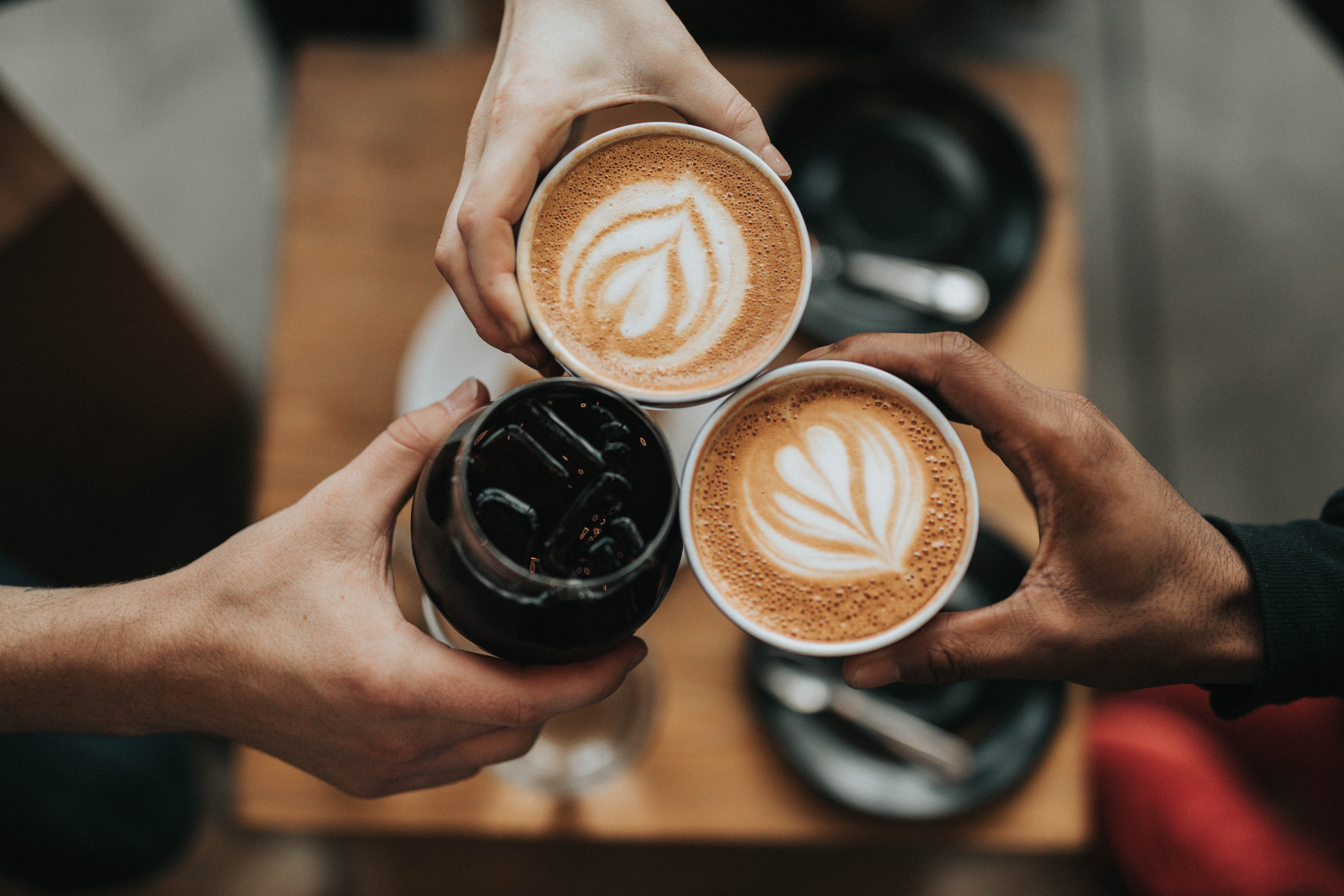 Tre par händer skolar i kaffe. 