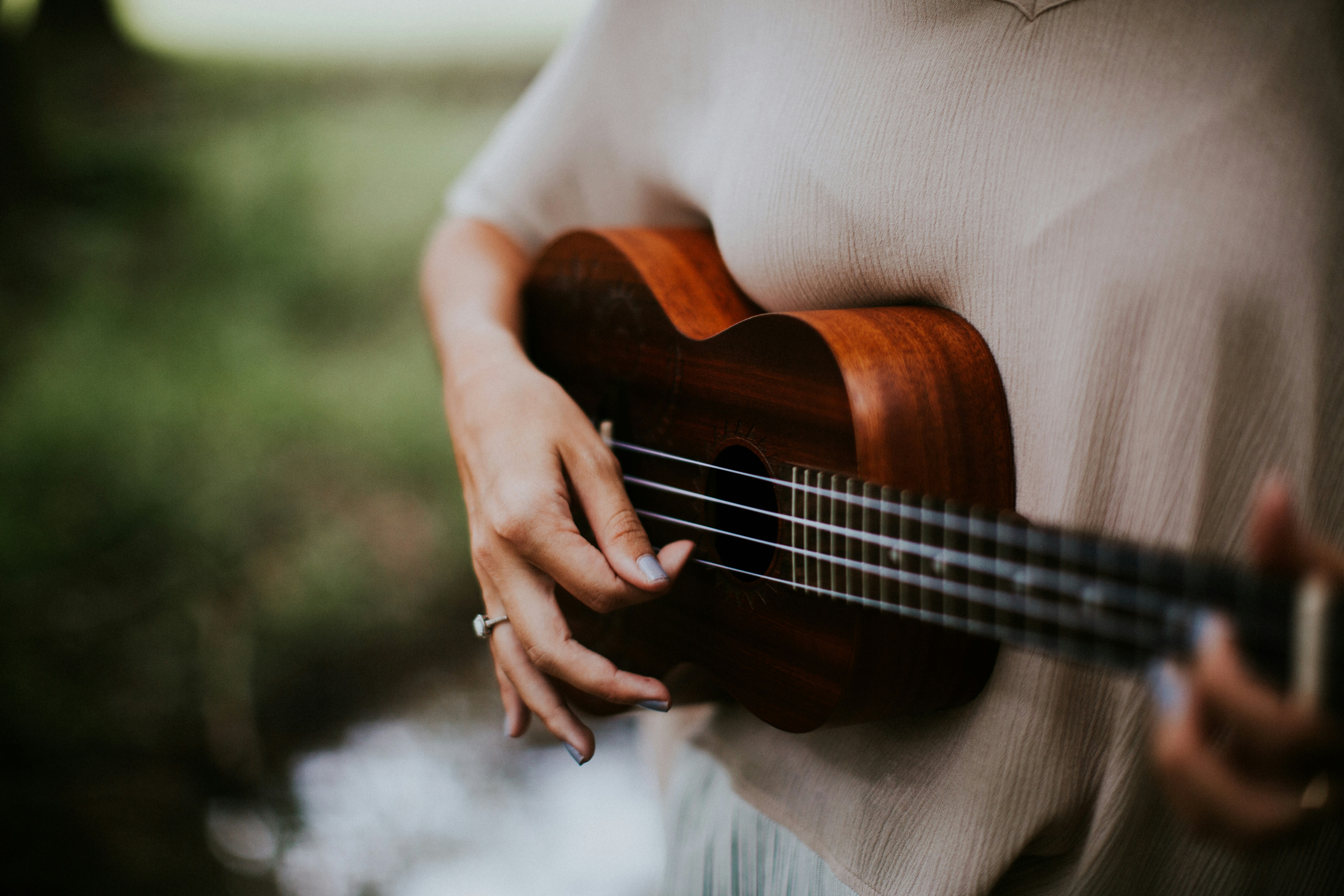 Kvinna som spelar gitarr i somrig miljö.