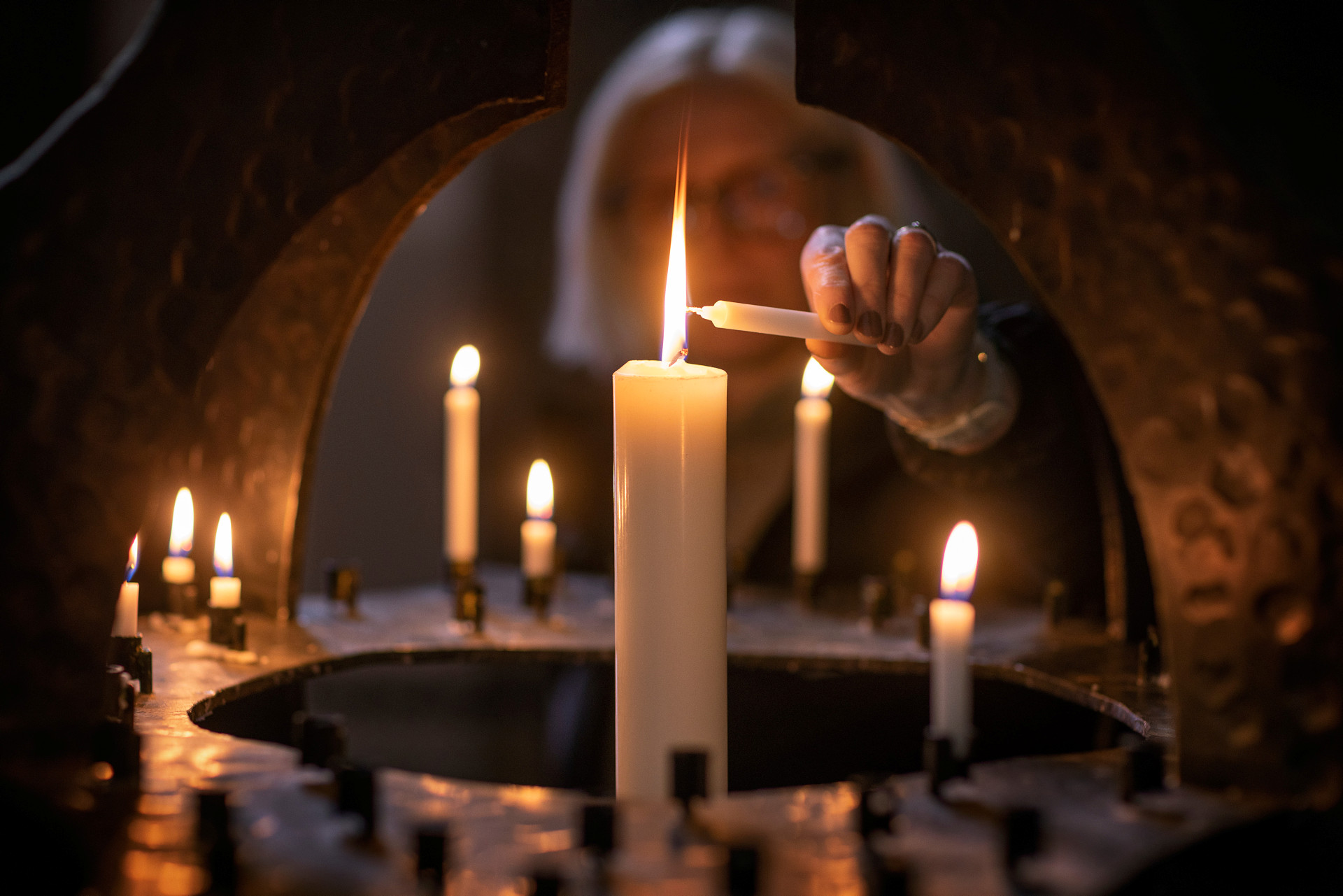 Kvinna tänder ljus i kyrka. 