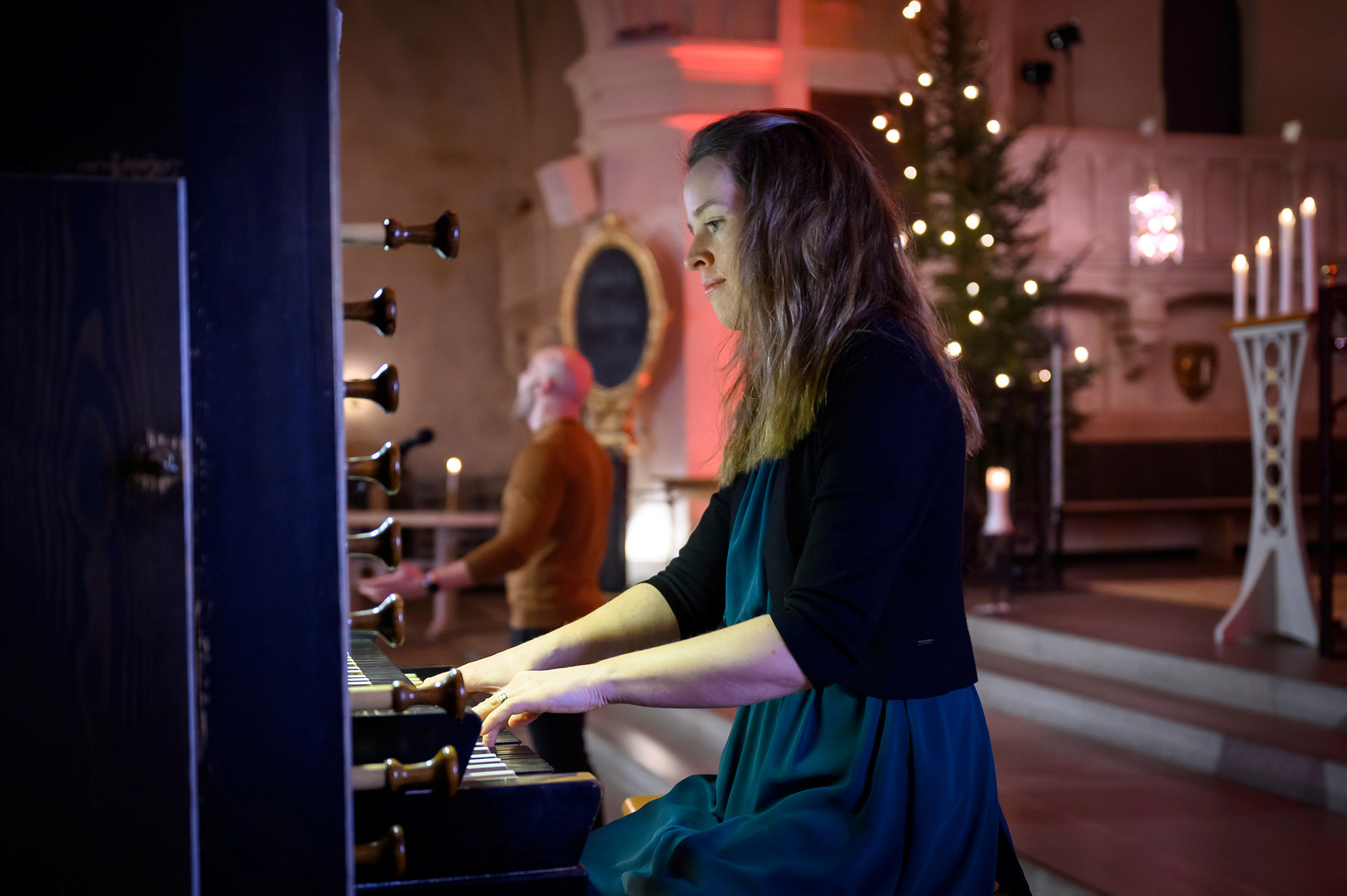En kvinna spelar kyrkoorgel i ett kyrkorum.