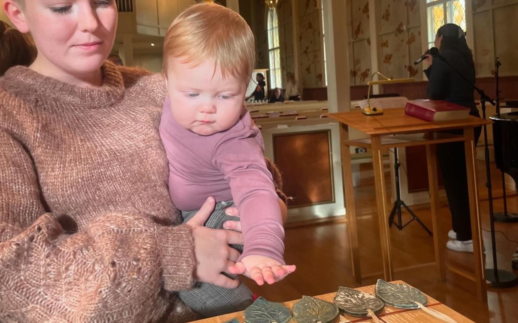 En mamma och sitt barn står framme vid altaret i kyrkan