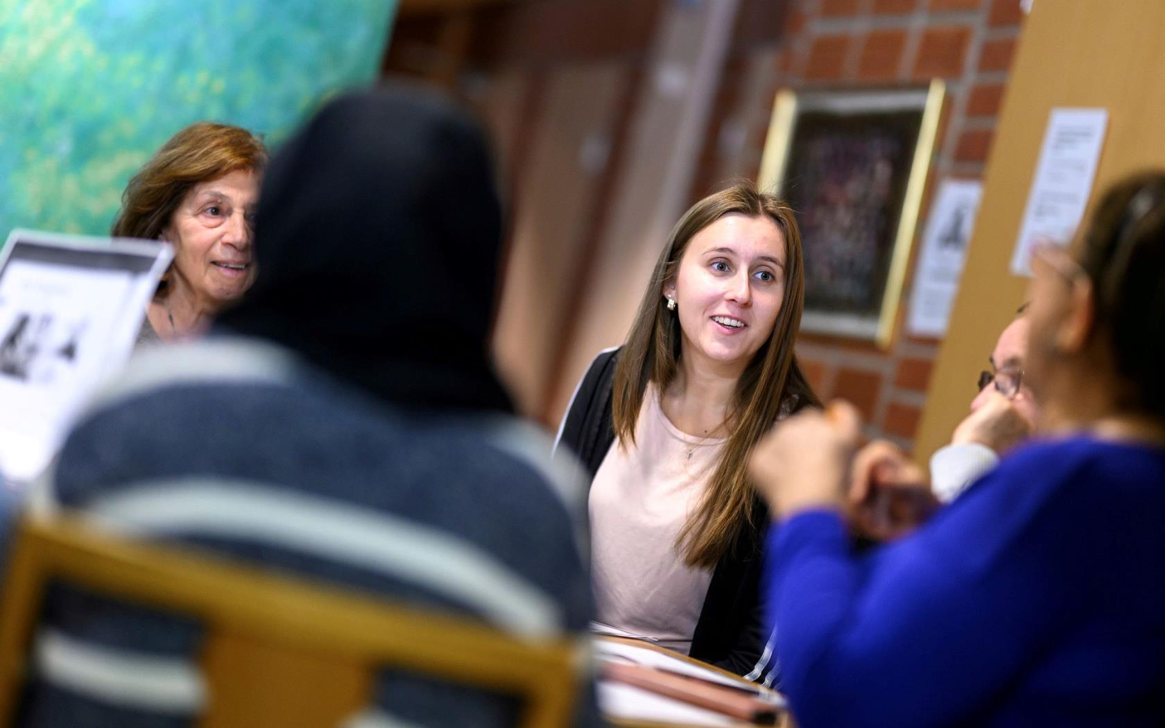 Några personer sitter och diskuterar glatt runt ett bord