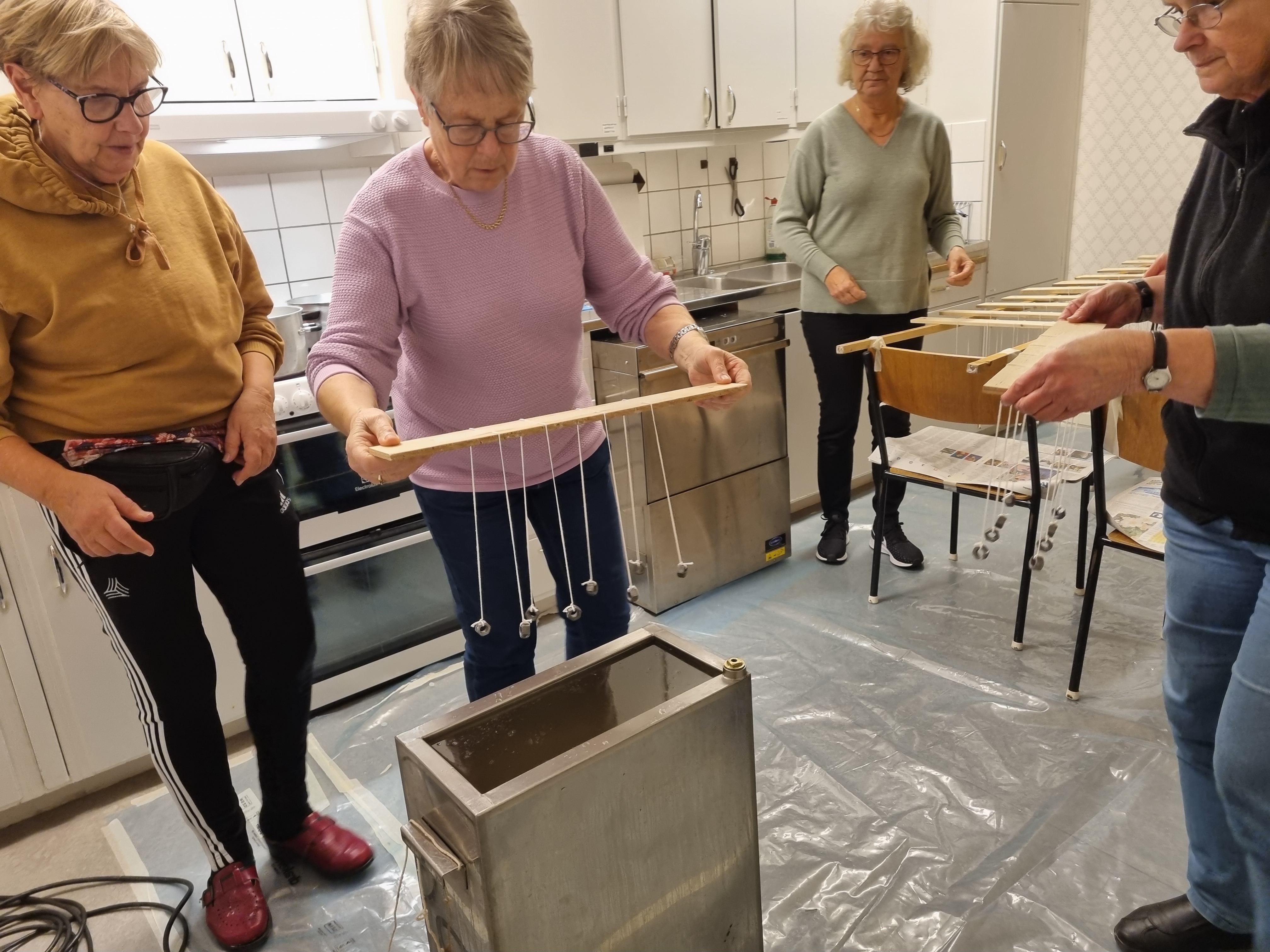 Tre damer stöper ljus i församlingshemmets kök