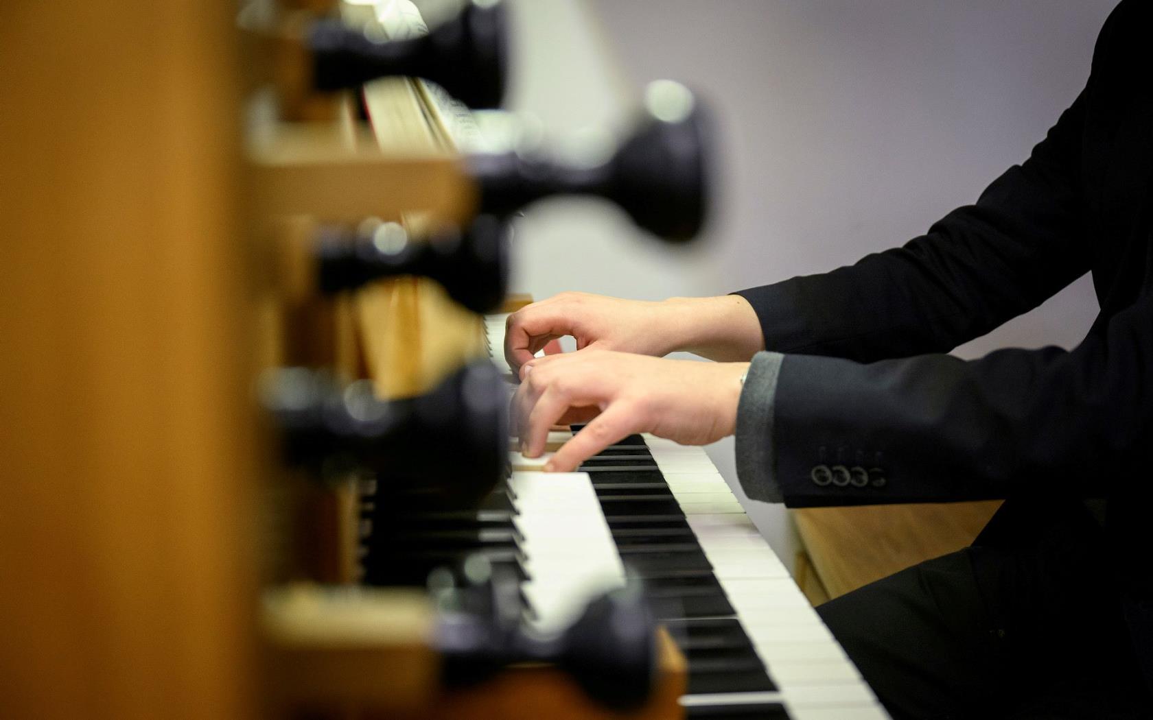 Någon i svart kavaj spelar orgel.