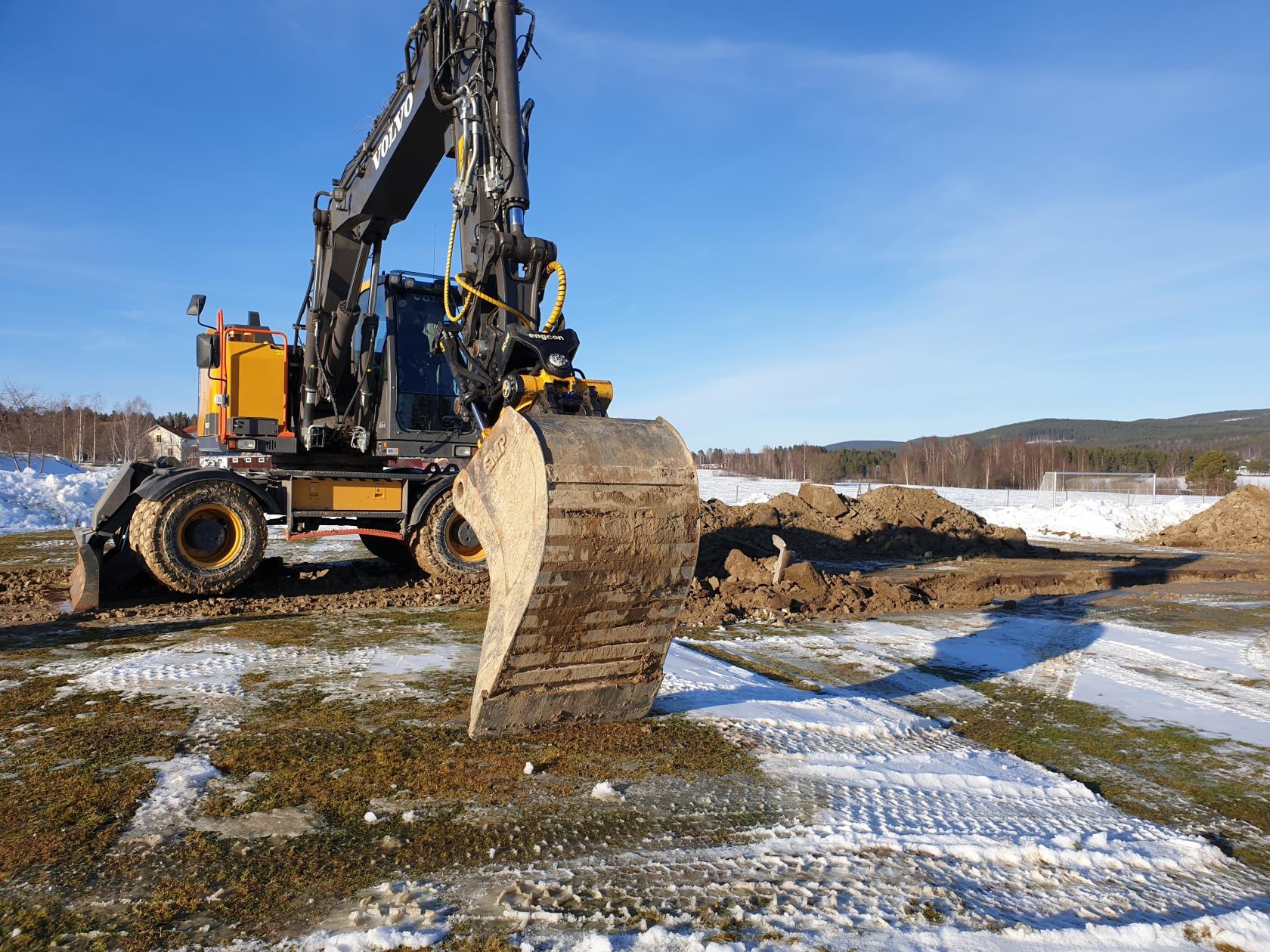 En grävmaskin i arbete på vintrigt underlag