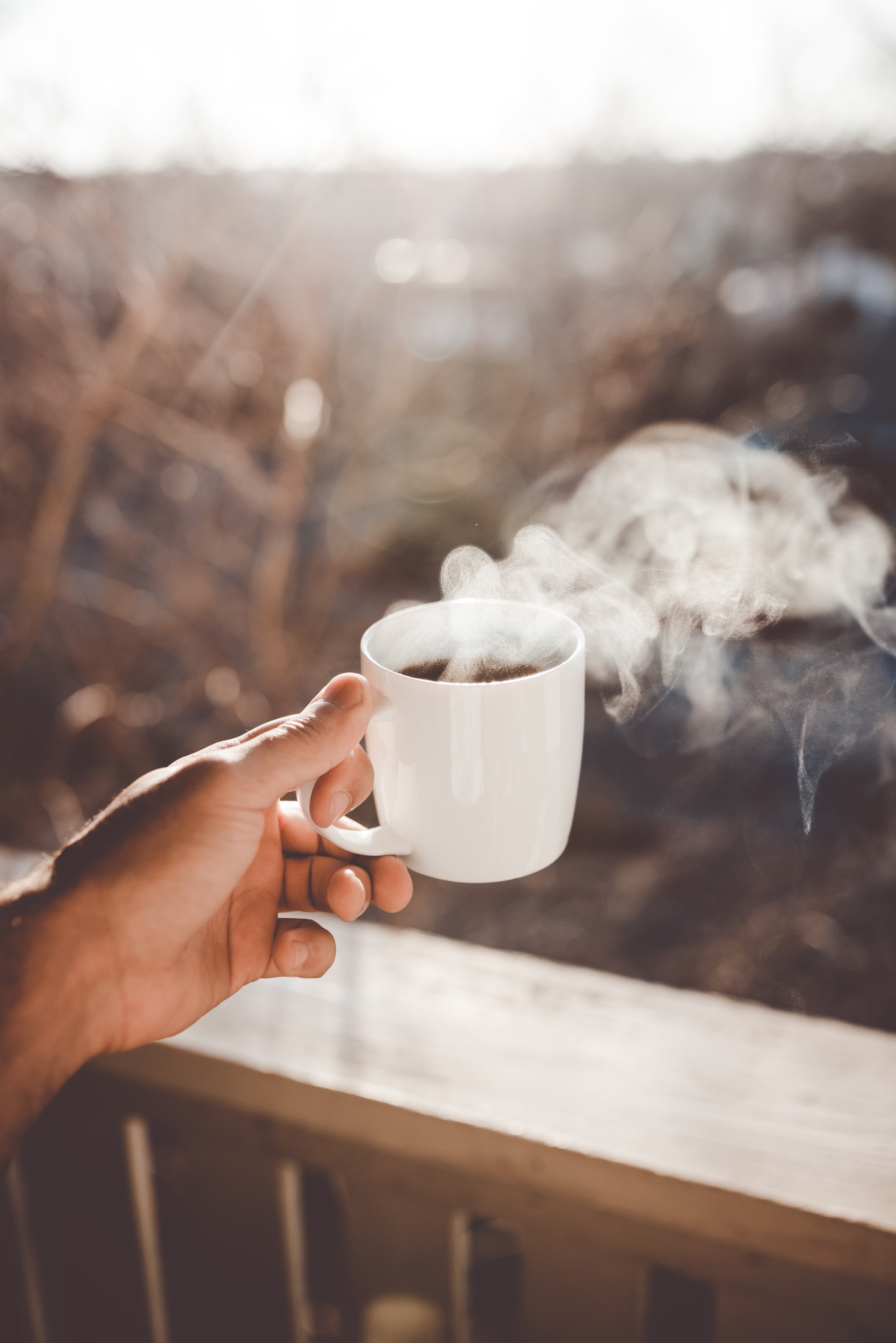 Hand som håller i en rykande kopp med svart kaffe.