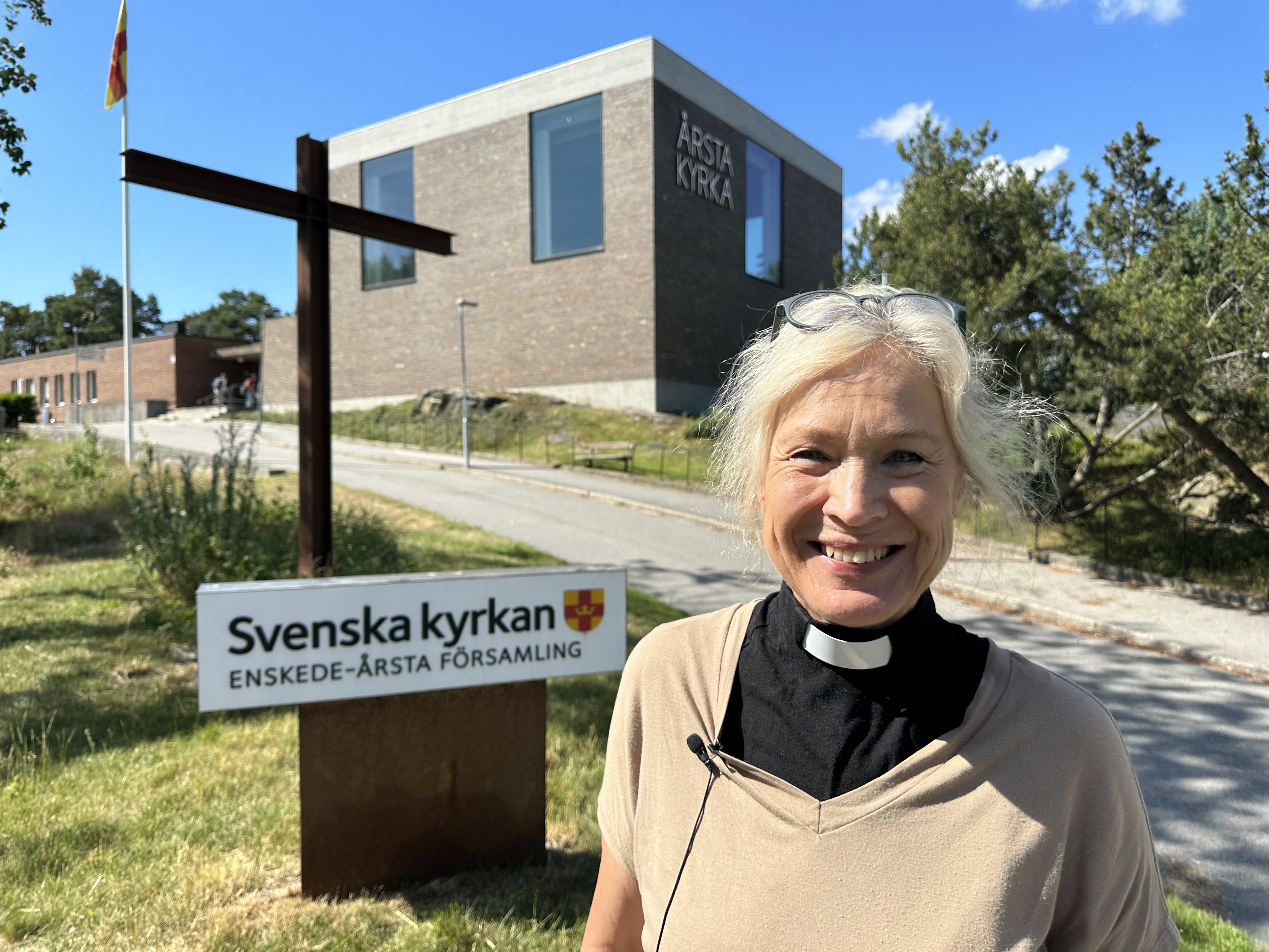 Kyrkoherde Marie Rehnstam utanför Årsta kyrka en solig sommardag