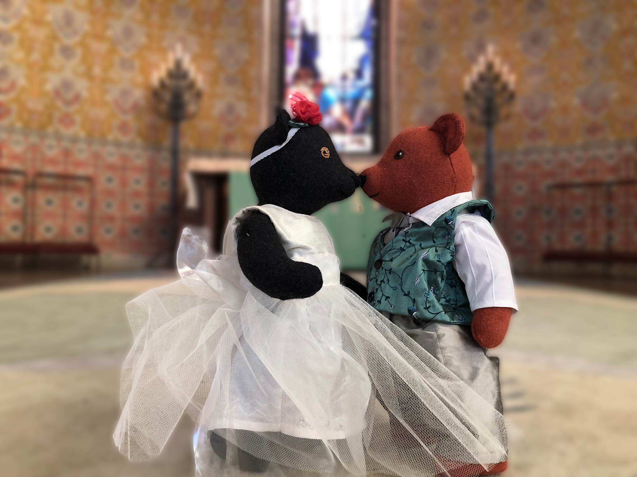 Två mjukisnallar klädda som ett brudpar framför altaret i Sundbybergs kyrka