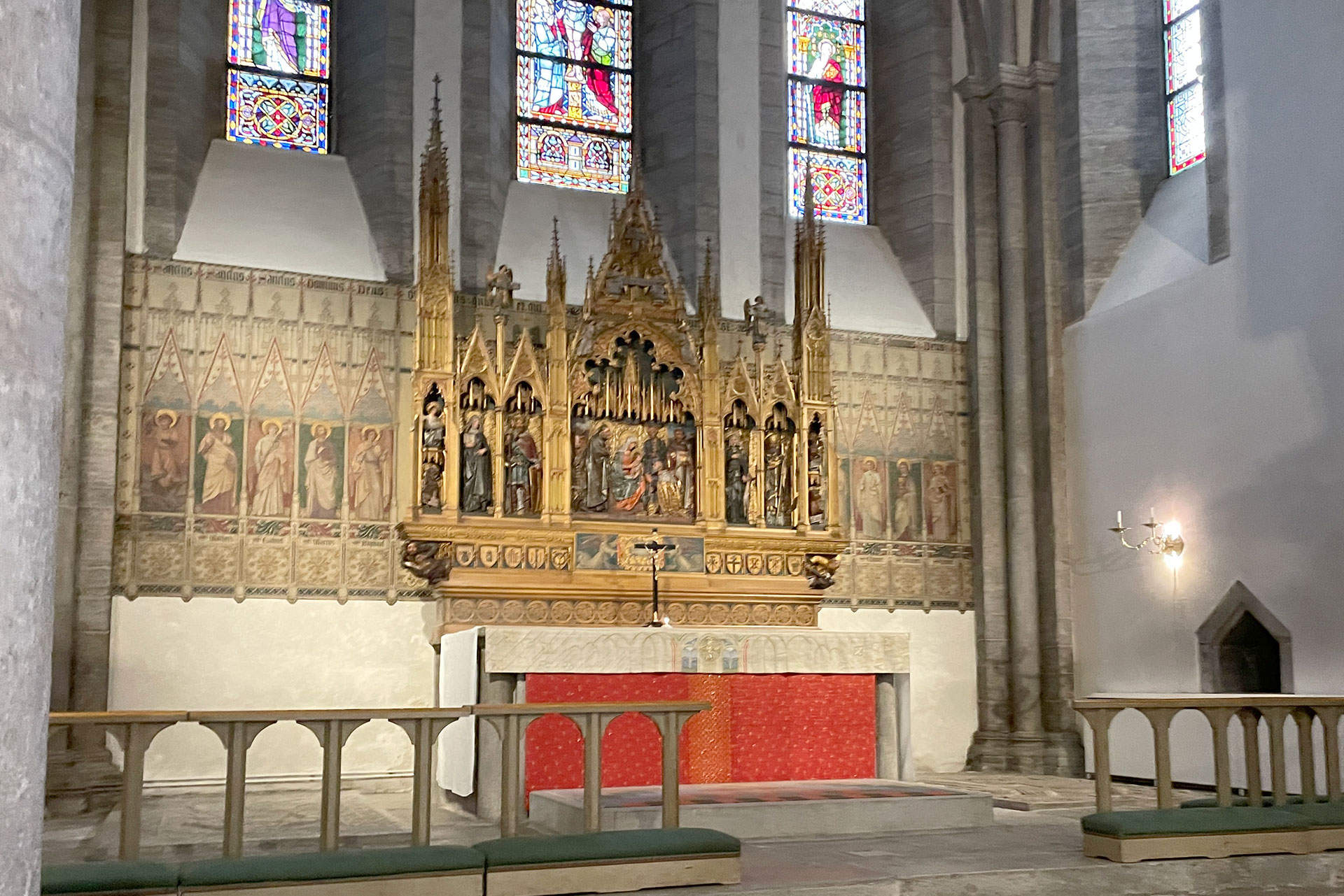 Högaltaret står i koret under de tre blyinfattade fönstren med olika bilder från bibeln