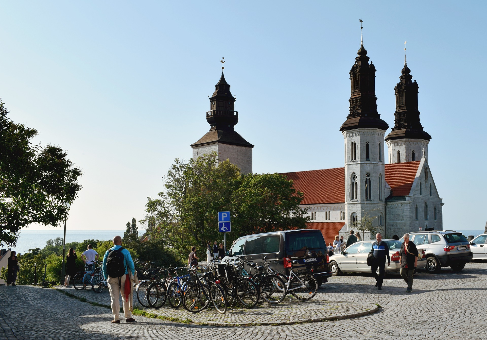 Människor promenerar över ett torg, med Visby Sankta Maria domkyrka i bakgrunden.