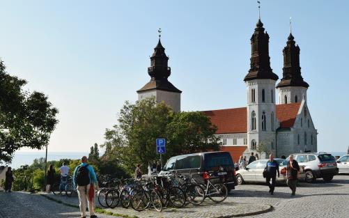 Människor promenerar över ett torg, med Visby Sankta Maria domkyrka i bakgrunden.