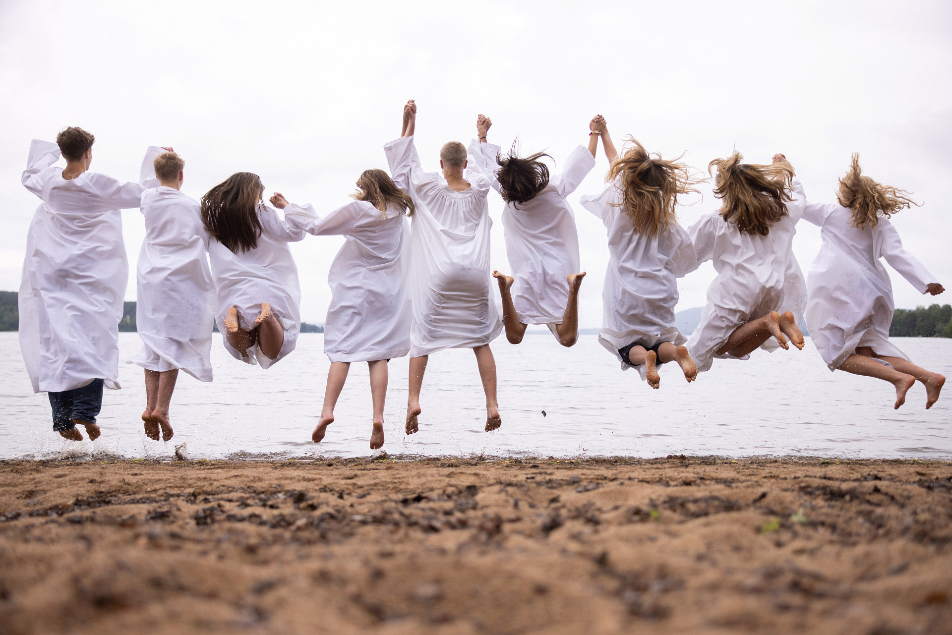 Konfirmander som hoppar vid en strand