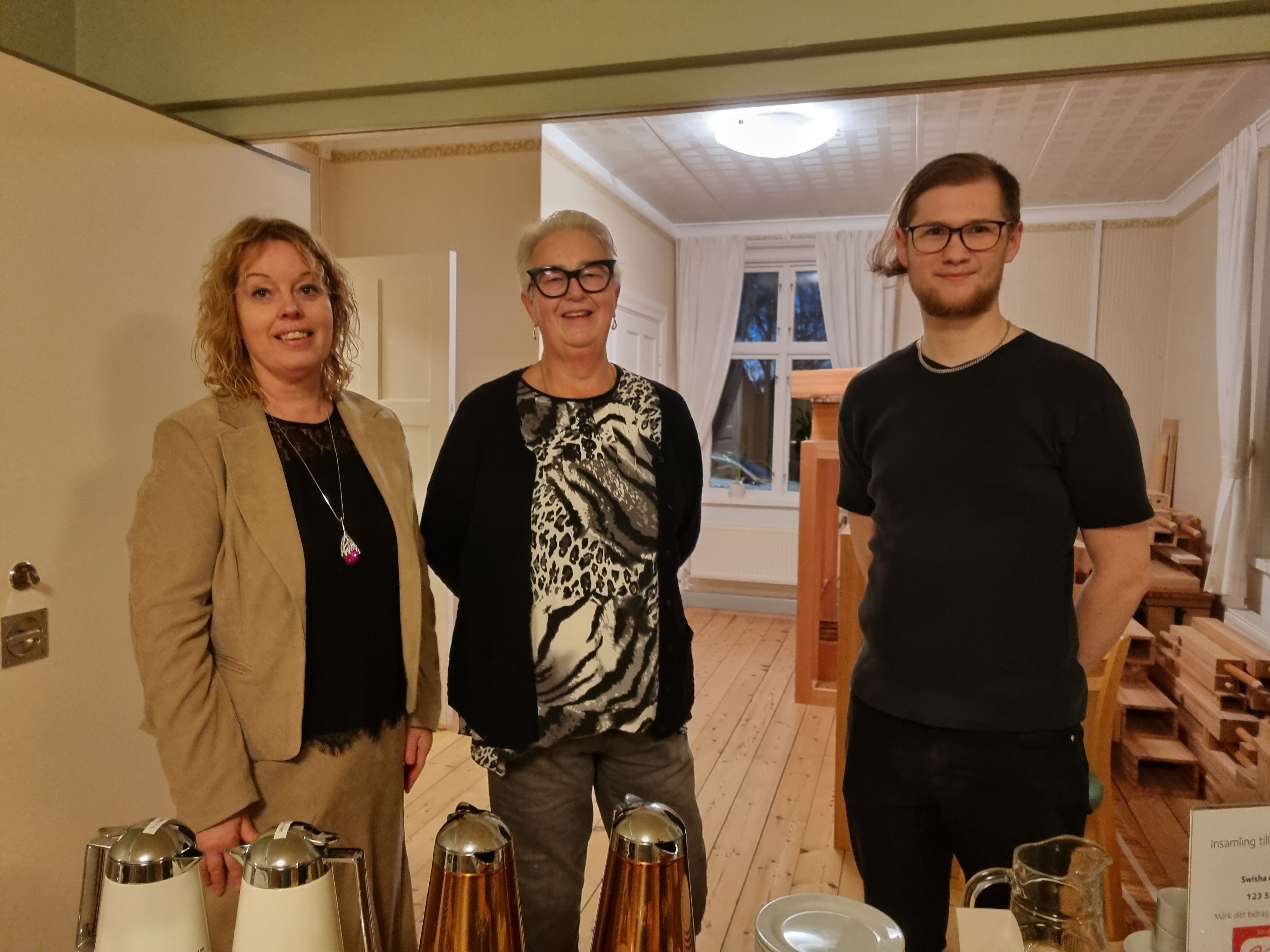 Tre personer står bakom ett bord med kaffebröd