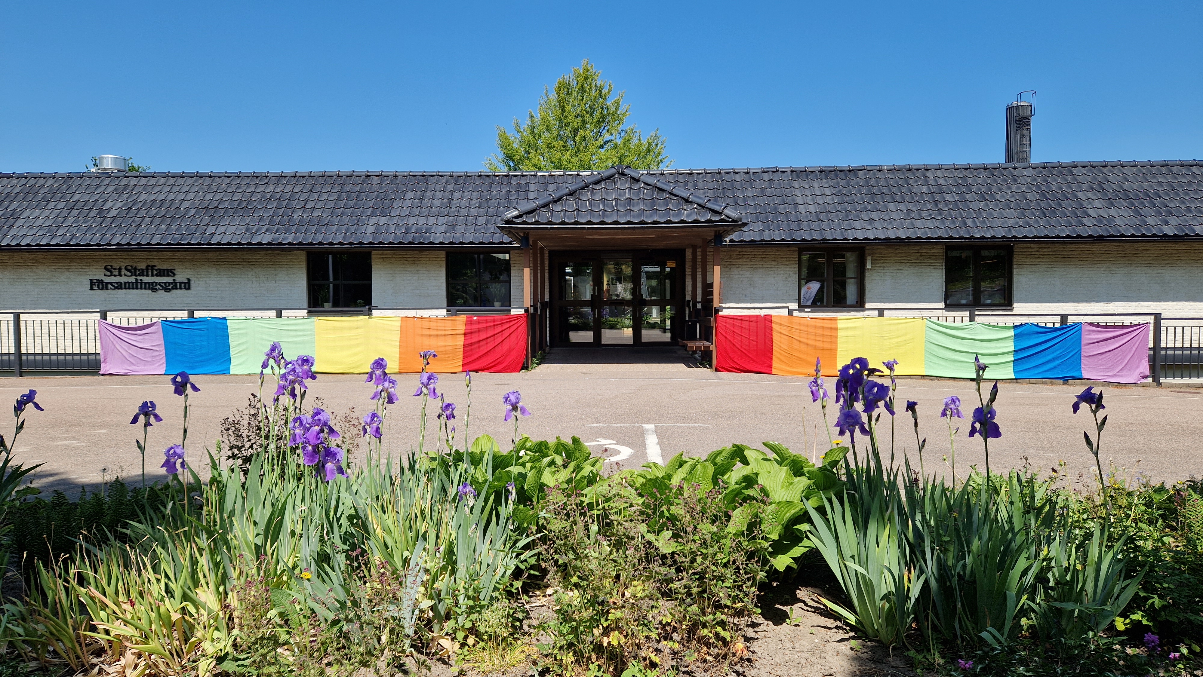 Regnbågsfärgat tyg på båda sidor om församlingsgårdens ingång.