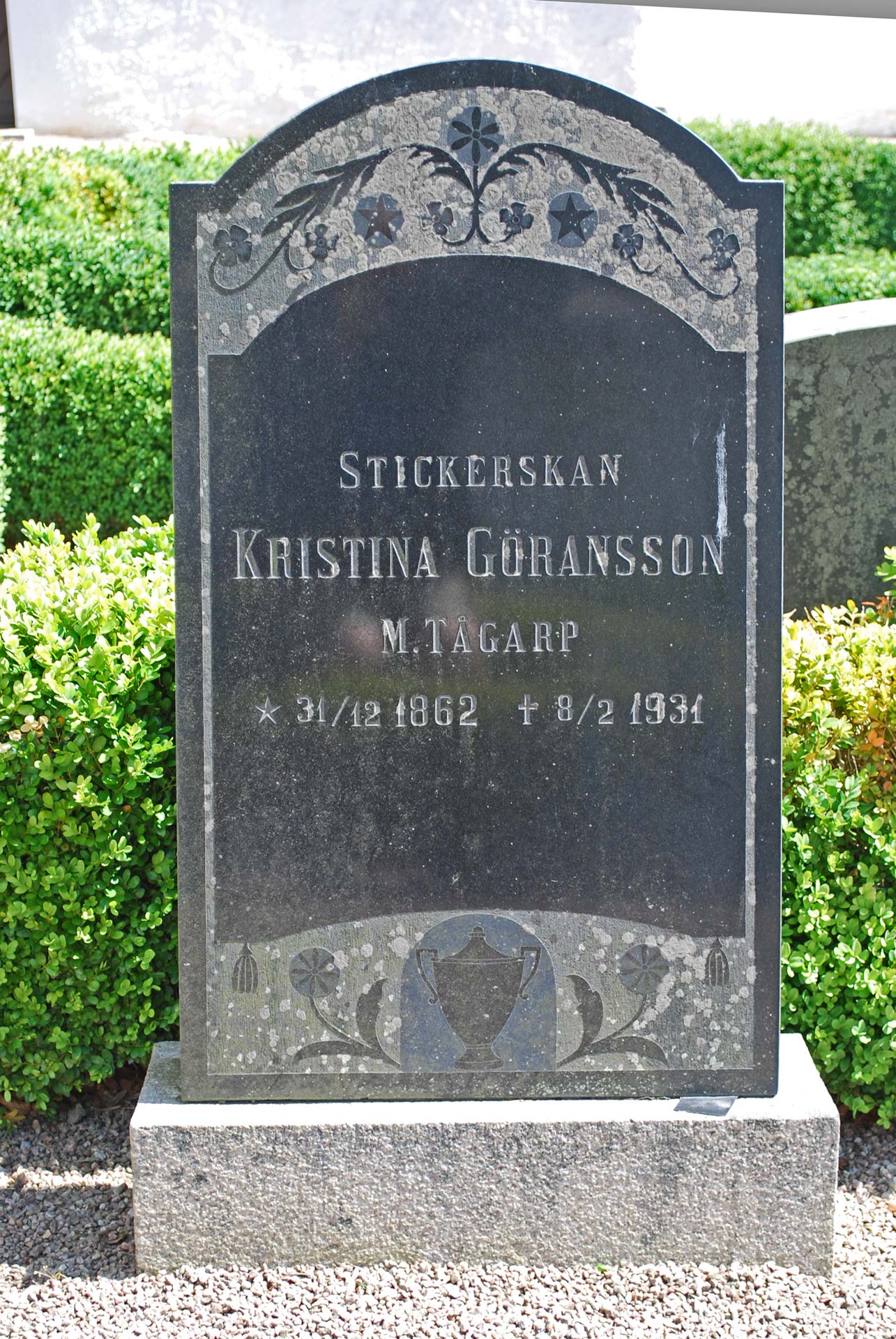 Kulturmärkt gravsten, dekorerad svart sten med texten Stickerskan Kristina Göransson, M,Tågarp 1862-1931