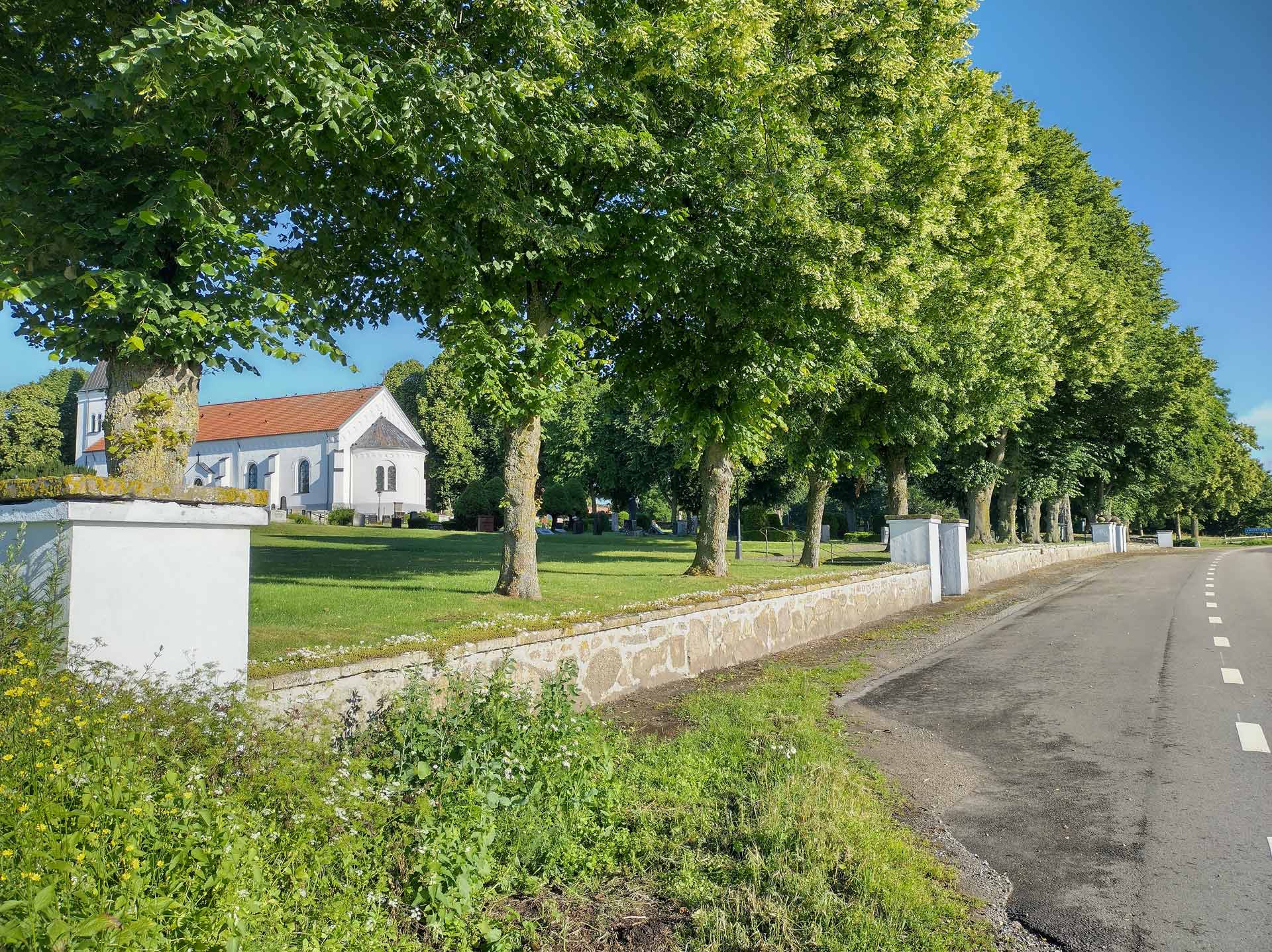 Kyrkomuren till kyrkogården i Smedstorp, med kyrkan  i bakgrunden.