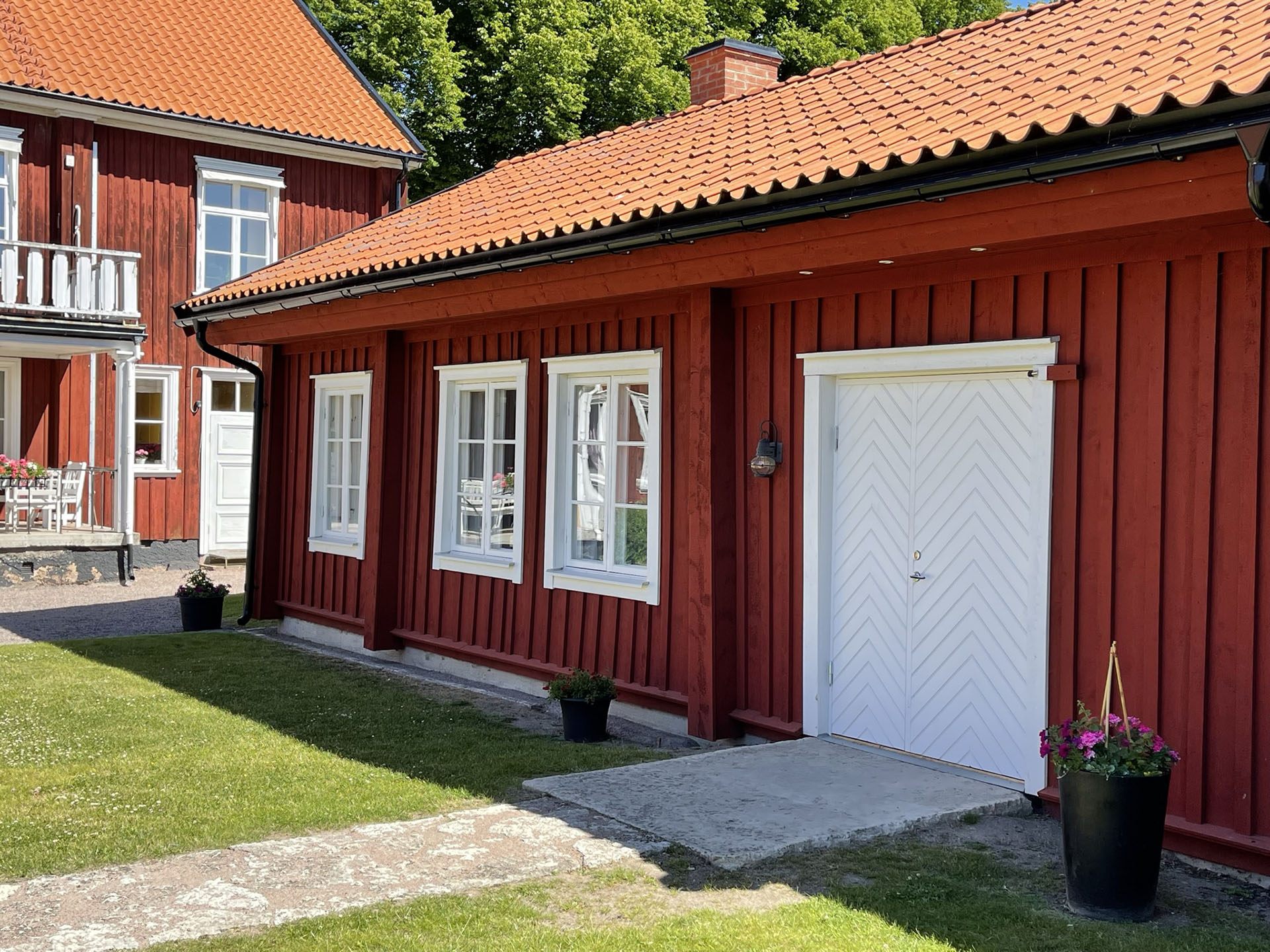 Det rödmålade Brygghuset i prästgårdsträdgården en solig sommardag