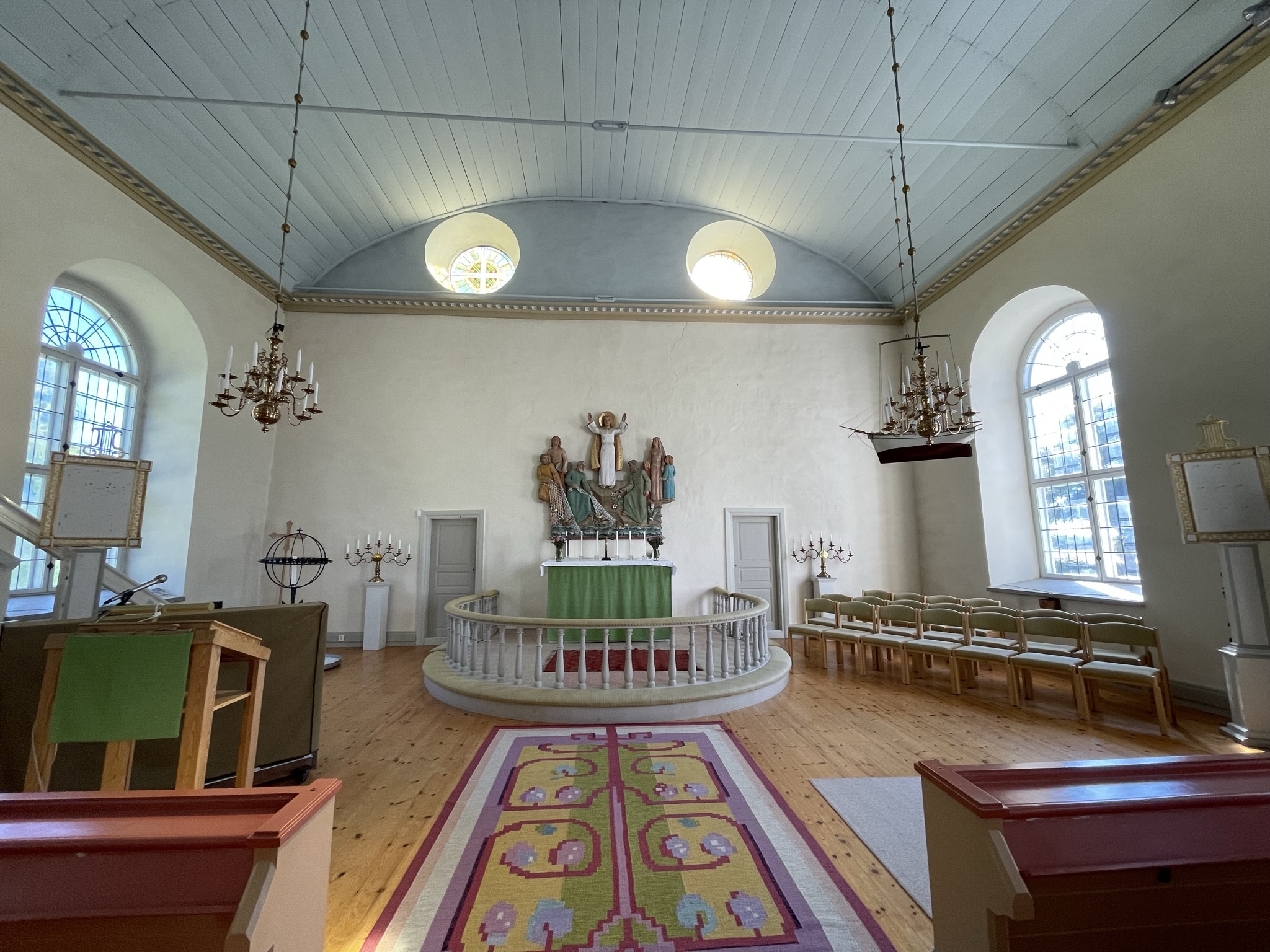 Kor i kyrka med ljusblått trätak och altarring i vitt trä.