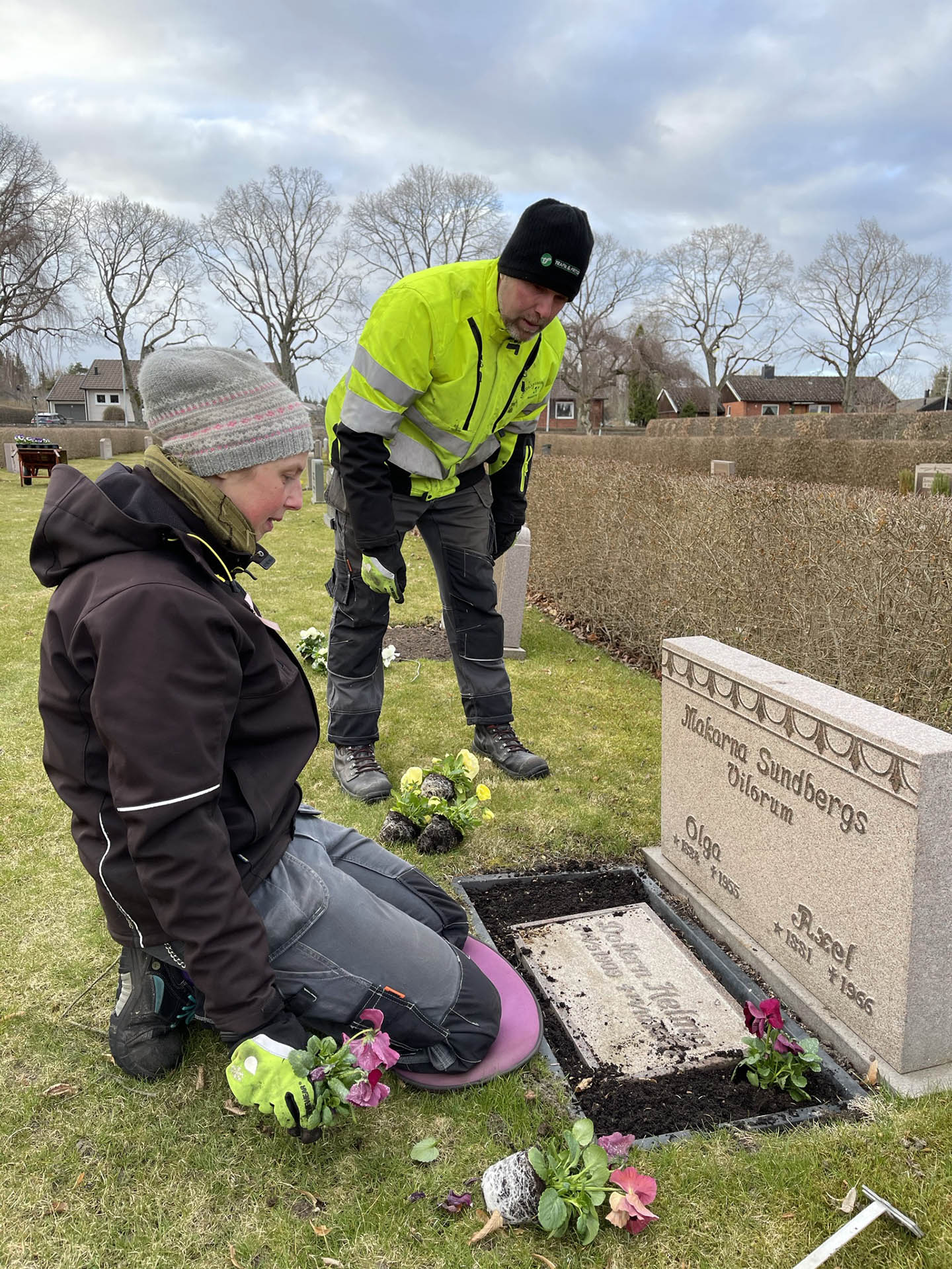 Kyrkogårdsarbetare planterar blommor vid en grav på Östra begravningsplatsen.