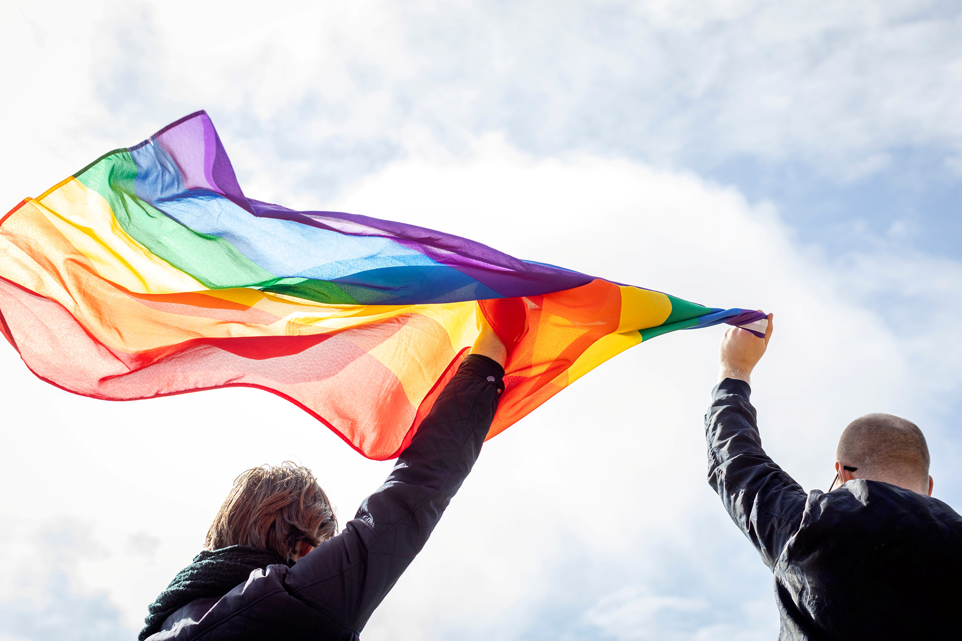 Bilden visar två personer som håller i en prideflagga