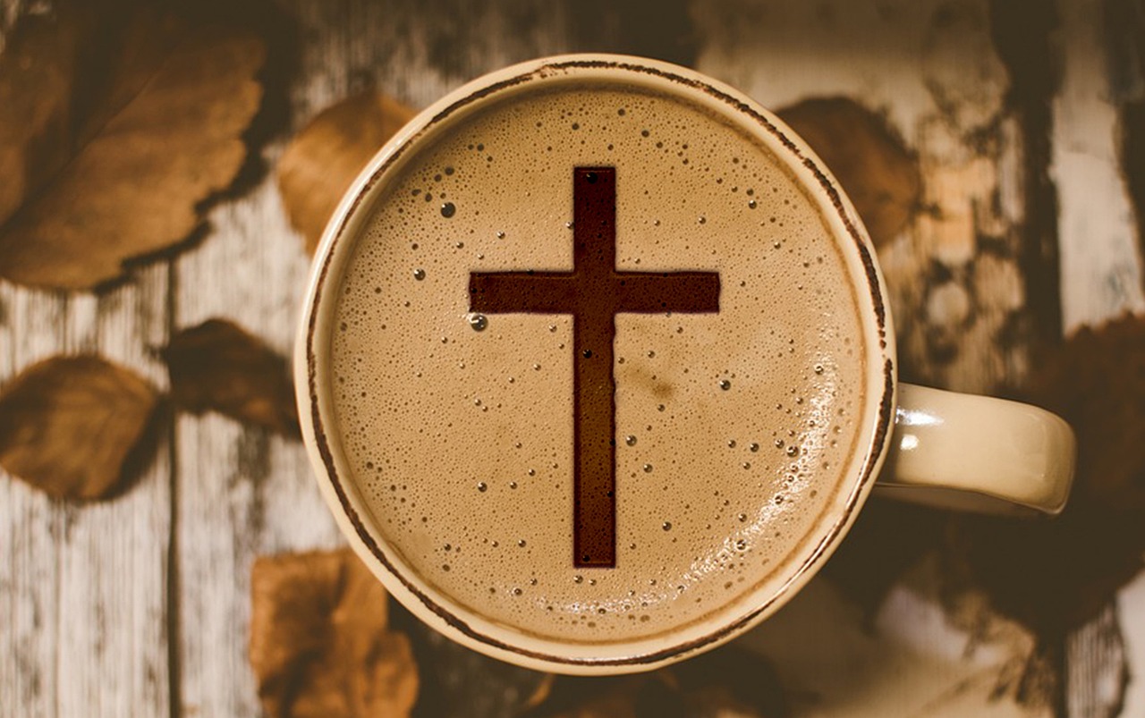 Bilden visar en mugg med kaffe och ett kors