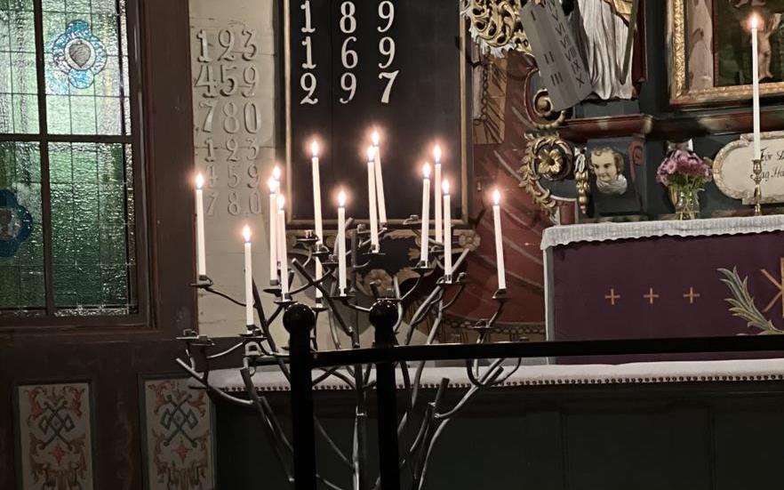 Några ljus brinner i ljusbäraren i Nysunds kyrka