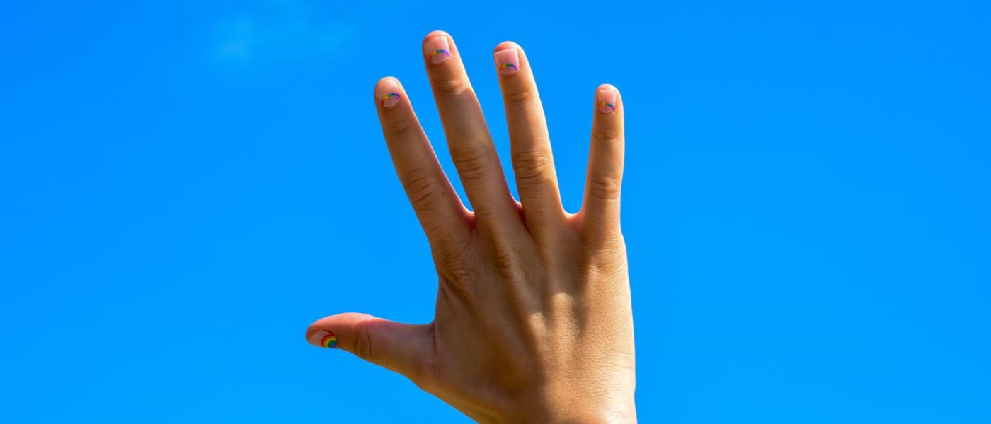 En hand sträckt mot den blå himlen.