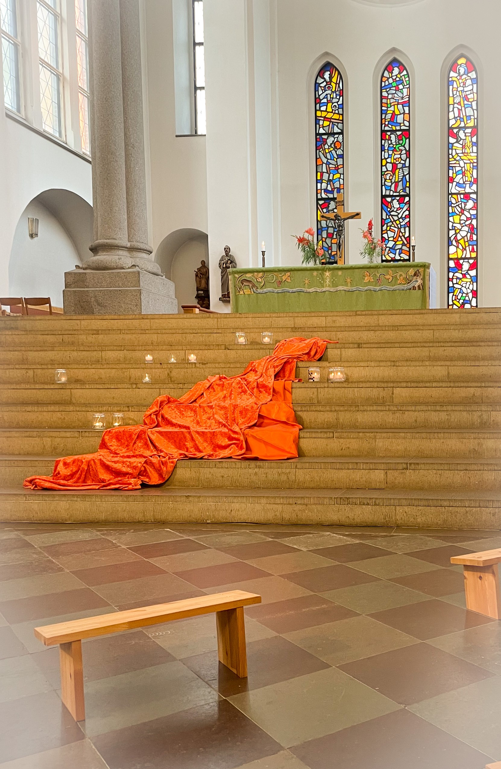 Orange tyg ligger på kyrktrappan med ljus runt omkring